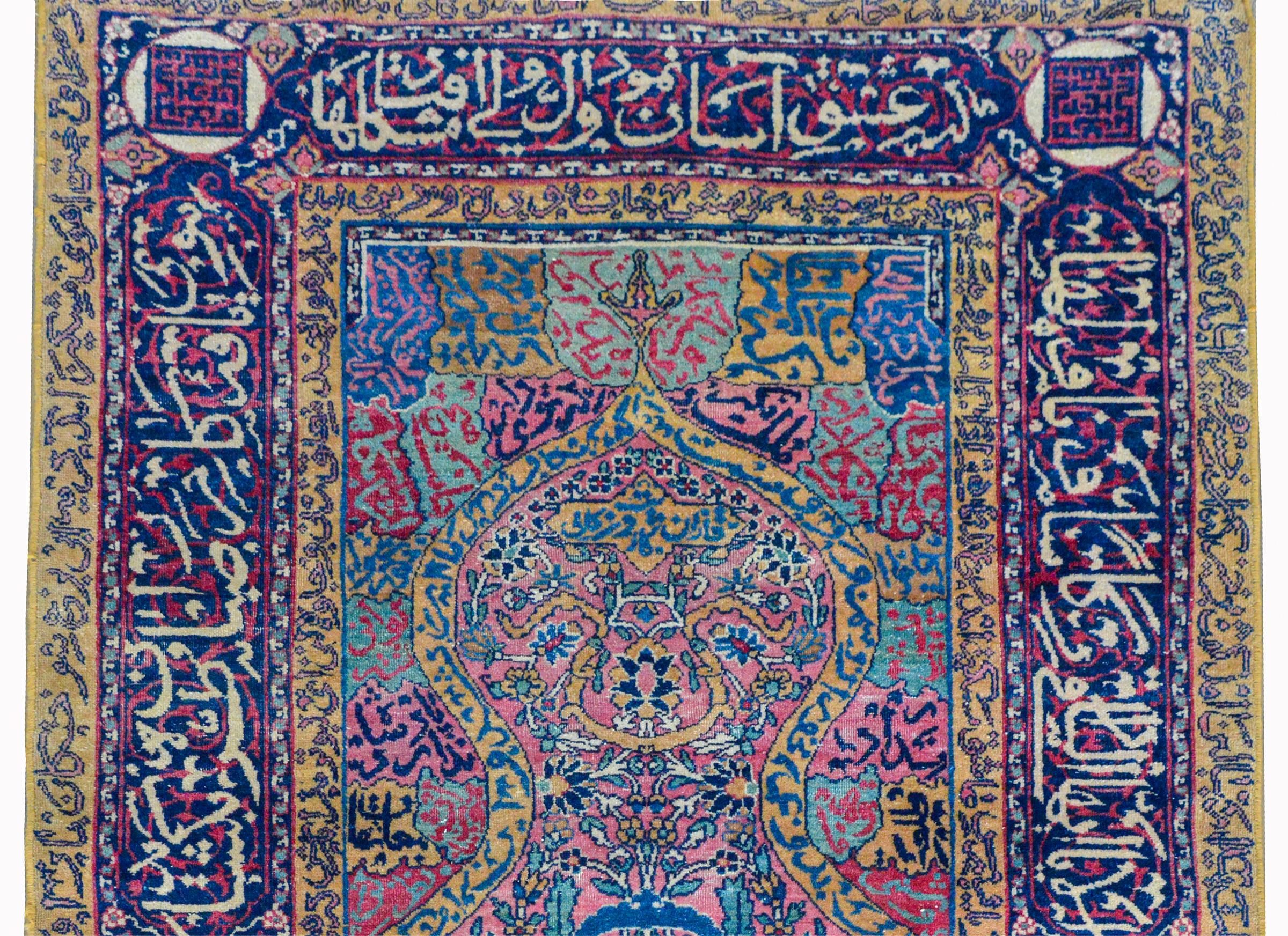 An extraordinary early 20th century Persian Kashan prayer rug with myriad floral and scrolling vine patterns woven in myriad colors, and surrounded by a border with scrolling vines and Persian script.