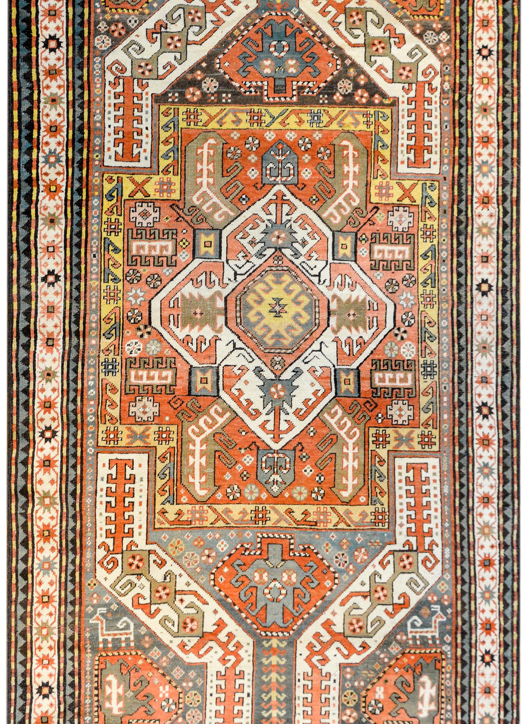An extraordinary early 20th century Azerbaijani Kazak rug of unusual color woven in beautiful crimson, gold, green, and pale indigo vegetable dyed wool colors. The pattern contains a large central diamond medallion with stylized leaves and scrolling