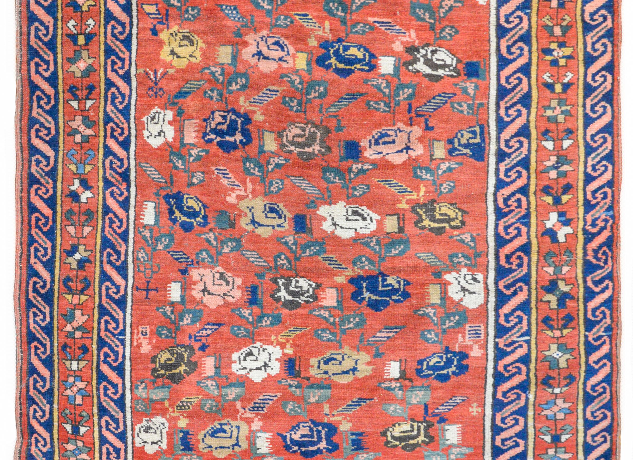 An extraordinary early 20th century Caucasian Karabagh rug with an all-over large scale rose pattern woven in white, brown, indigo, gold, and pink with green leaves, and all against a crimson background. The border is wonderful with a central
