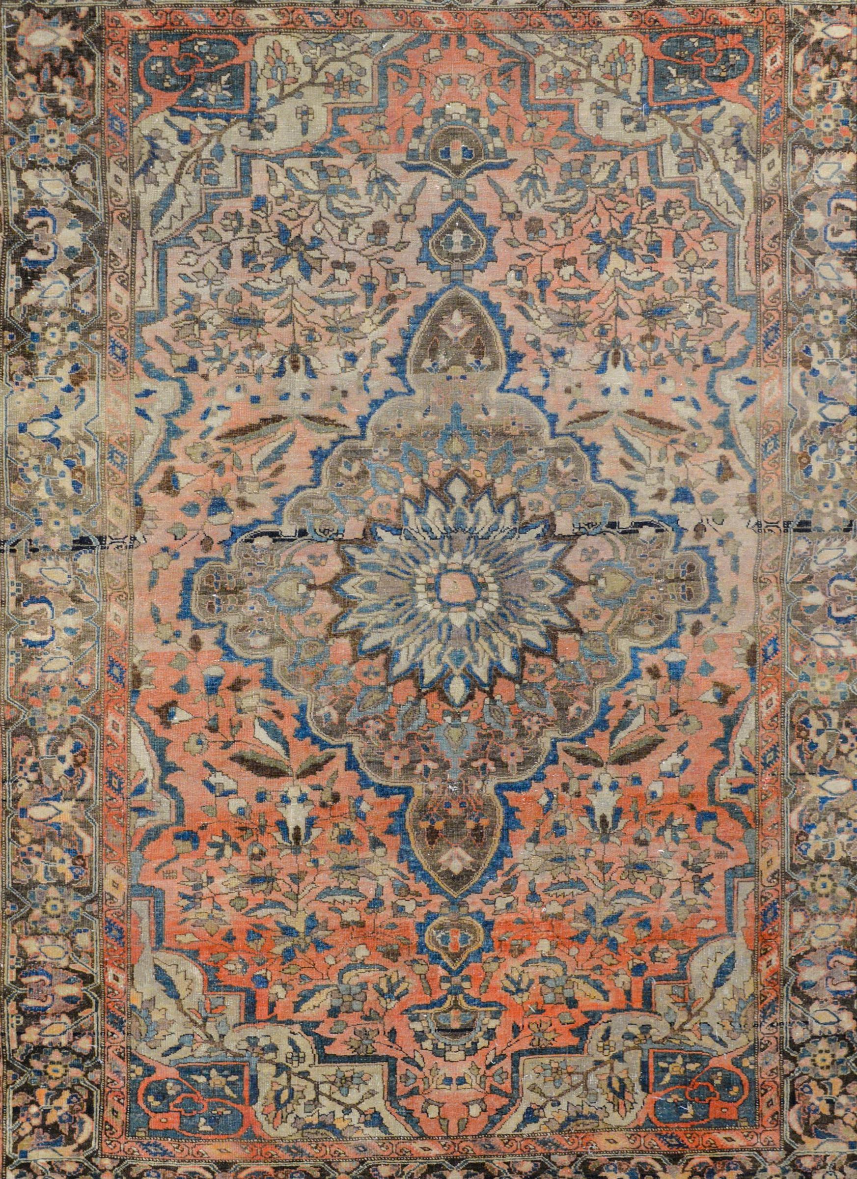 An extraordinary early 20th century Sarouk Farahan rug with a large central floral medallion woven in light and dark indigo, cream, pale green, and brown colored vegetable dyed wool, all on an abrash coral background. The border is fascinating with