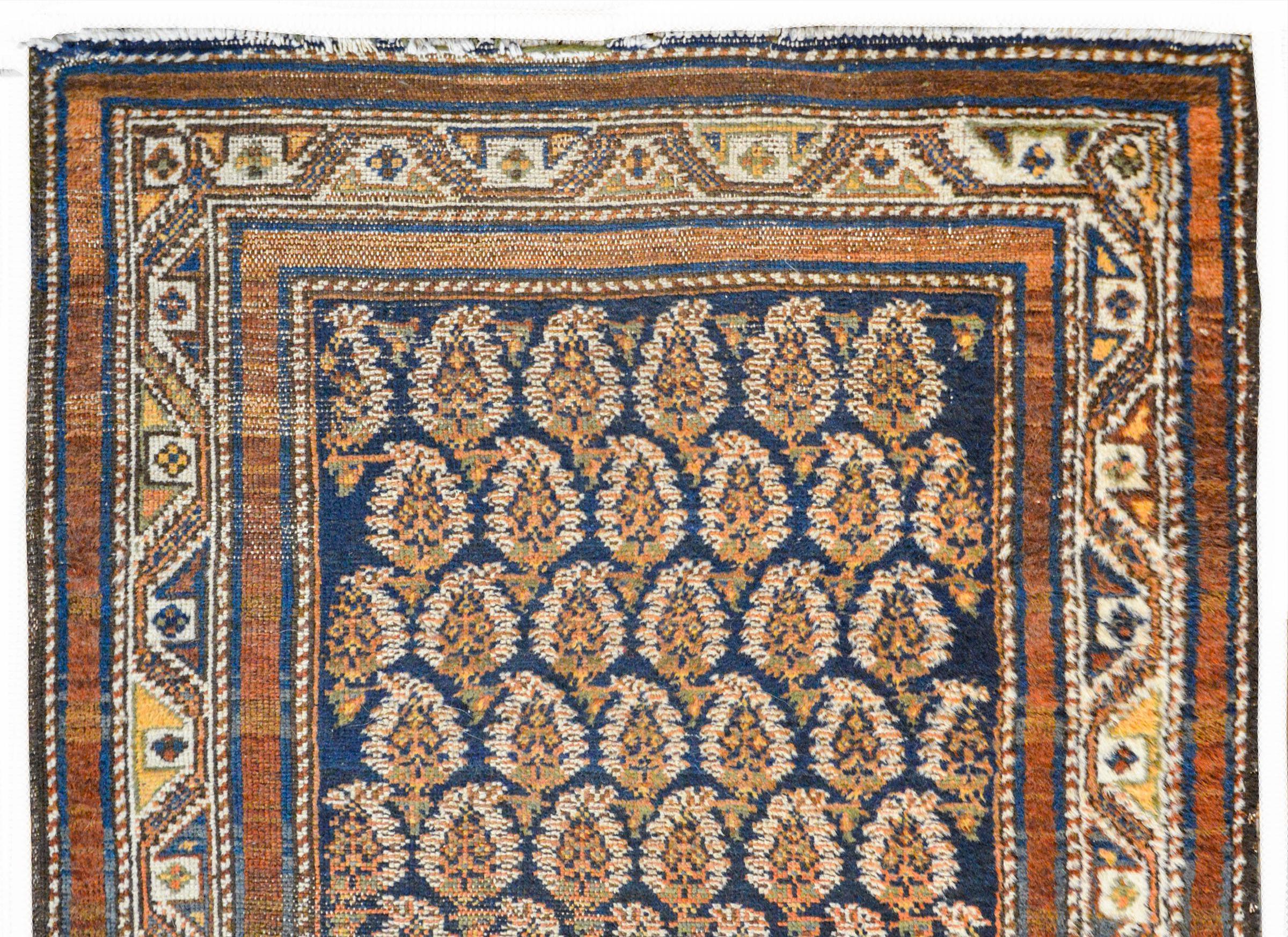 An extraordinary early 20th century Persian Seraband runner with an all-over paisley pattern woven in multiple colors against a dark indigo background surrounded by a border with a central stylized floral and scrolling vine pattern flanked by pairs
