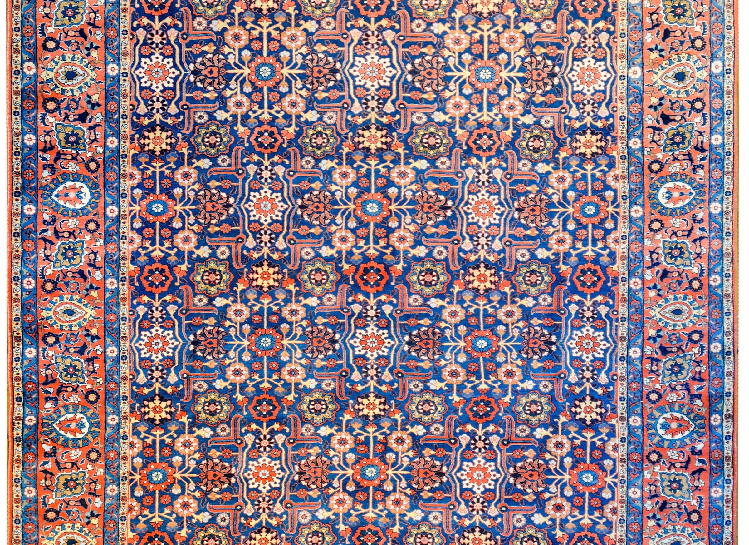A wonderful early 20th century Persian Yazd rug with a trellis floral pattern woven in a rich crimson, gold, and cream colored vegetable dyed wool on a dark indigo background. The border is extraordinary and complex with a wide floral and vine