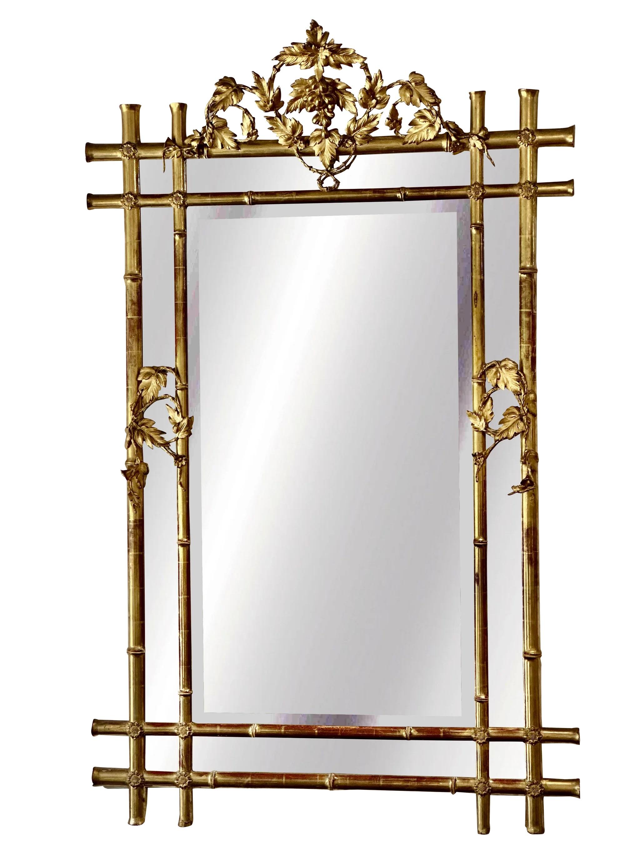 A period French Louis Philippe giltwood and gesso looking glass, the large form with a faux bamboo frame accented with grape and vine continuing to the grape cluster crest, overall 70