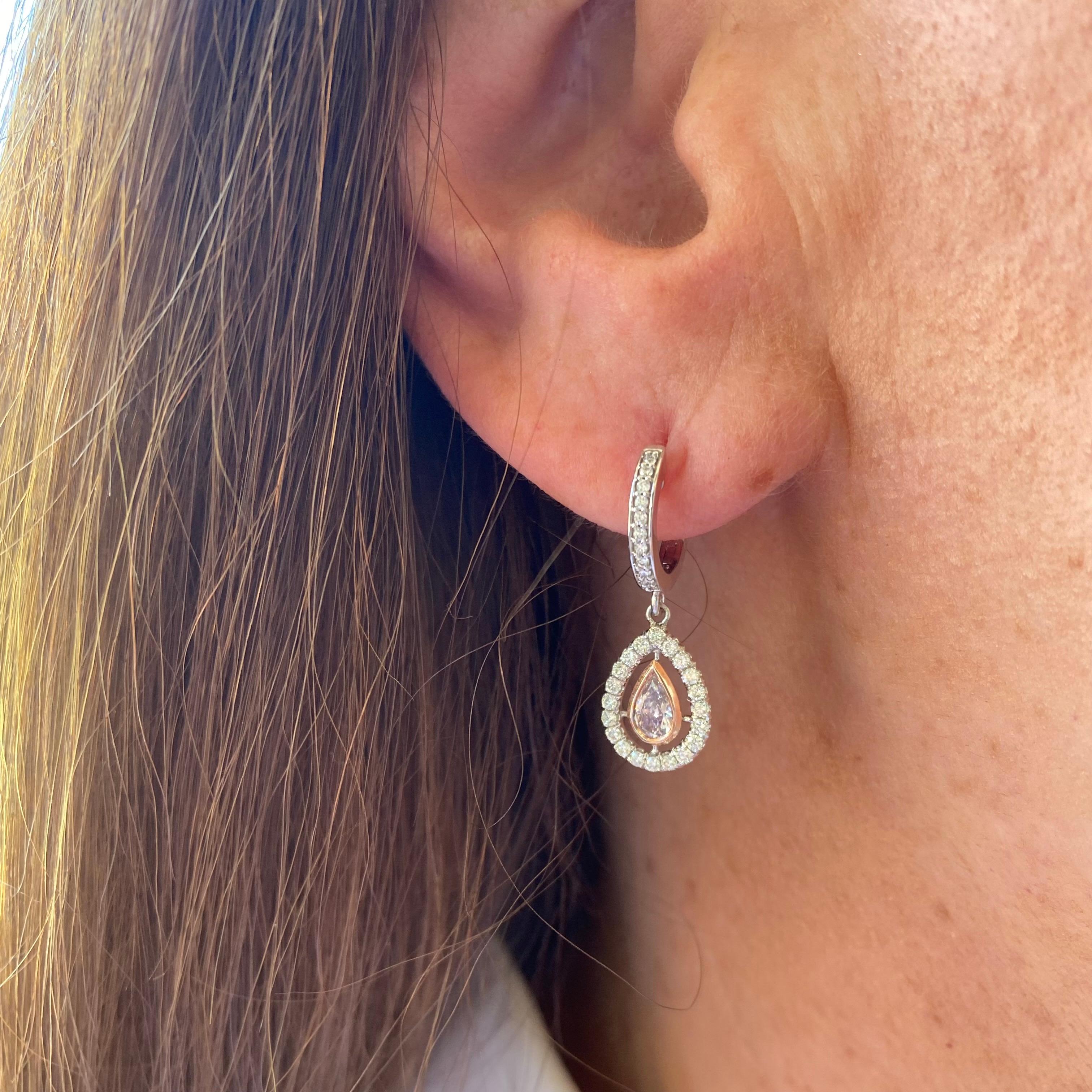 If you're searching for a fabulous pair of earrings, search no more! This exceptional pair features two rare GIA pink pear shaped diamonds expertly set in 18 karat pink gold, surrounded by a halo of fine white diamonds set in 18 karat white gold for