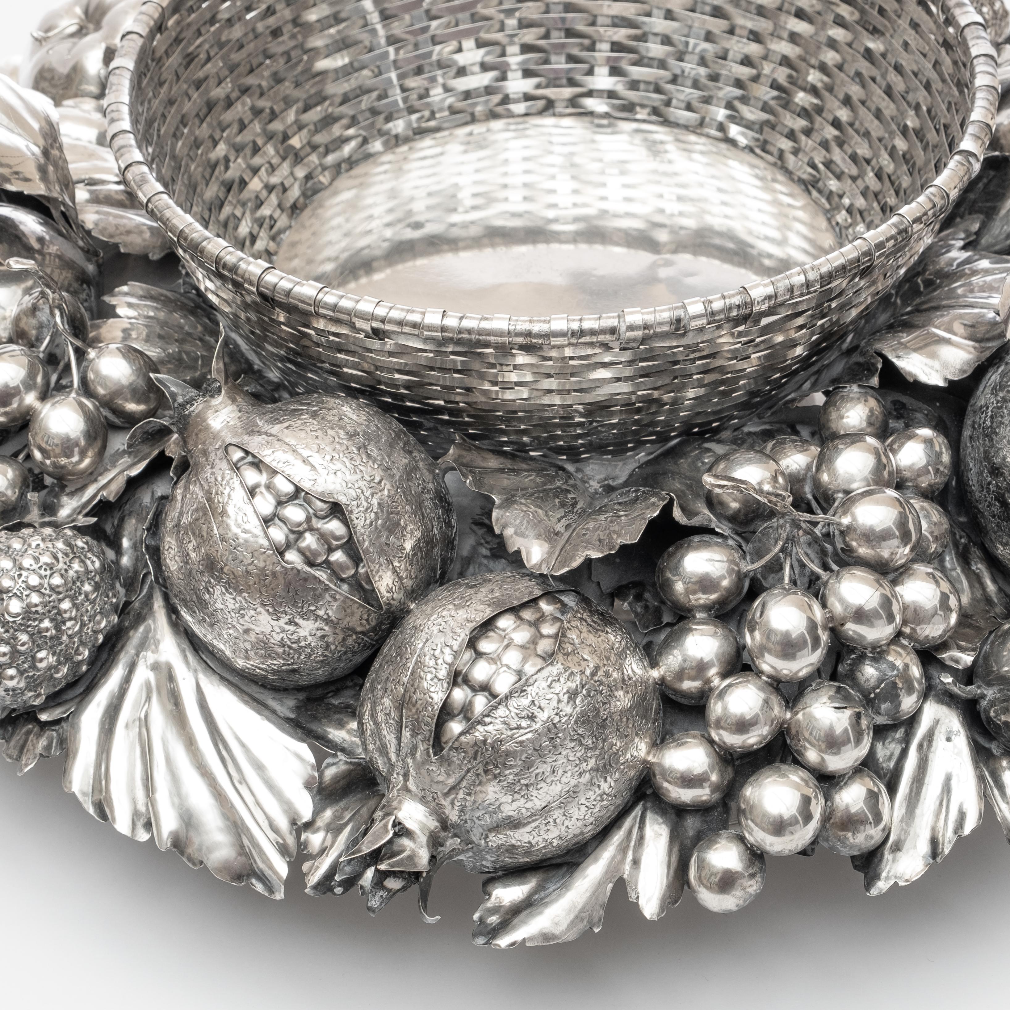 Substantial Gianmaria Buccellati silver centerpiece bowl having woven circular basket centered by sculpted silver fruit and foliate, comprising of various leaves and stemmed fruits to include pears, strawberries, apples, grapes, pomegranate, figs