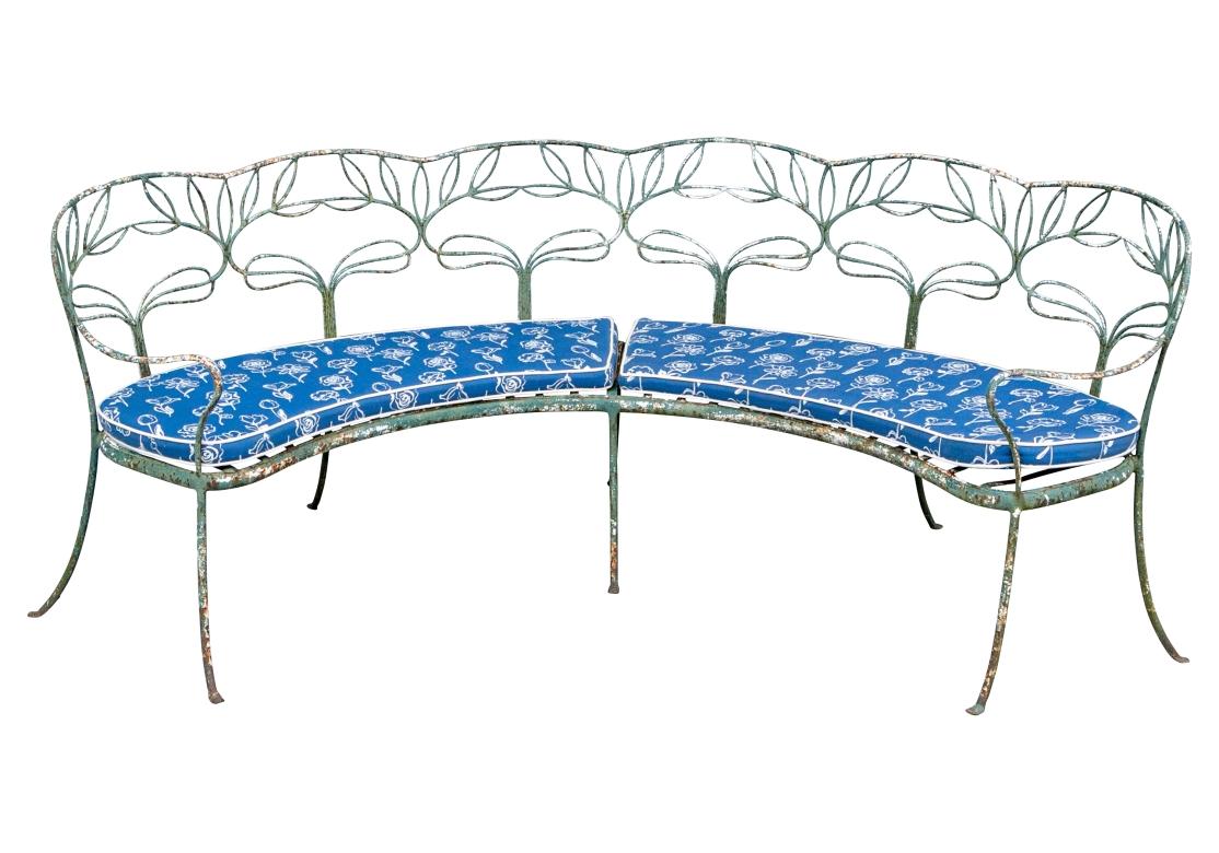 An extraordinary early 20th Century Garden Bench with fine form and artistic scrolling Ironwork. It A large curved wrought iron garden bench constructed with rods of iron with openwork foliate back sections and a scalloped crest rail. With curved