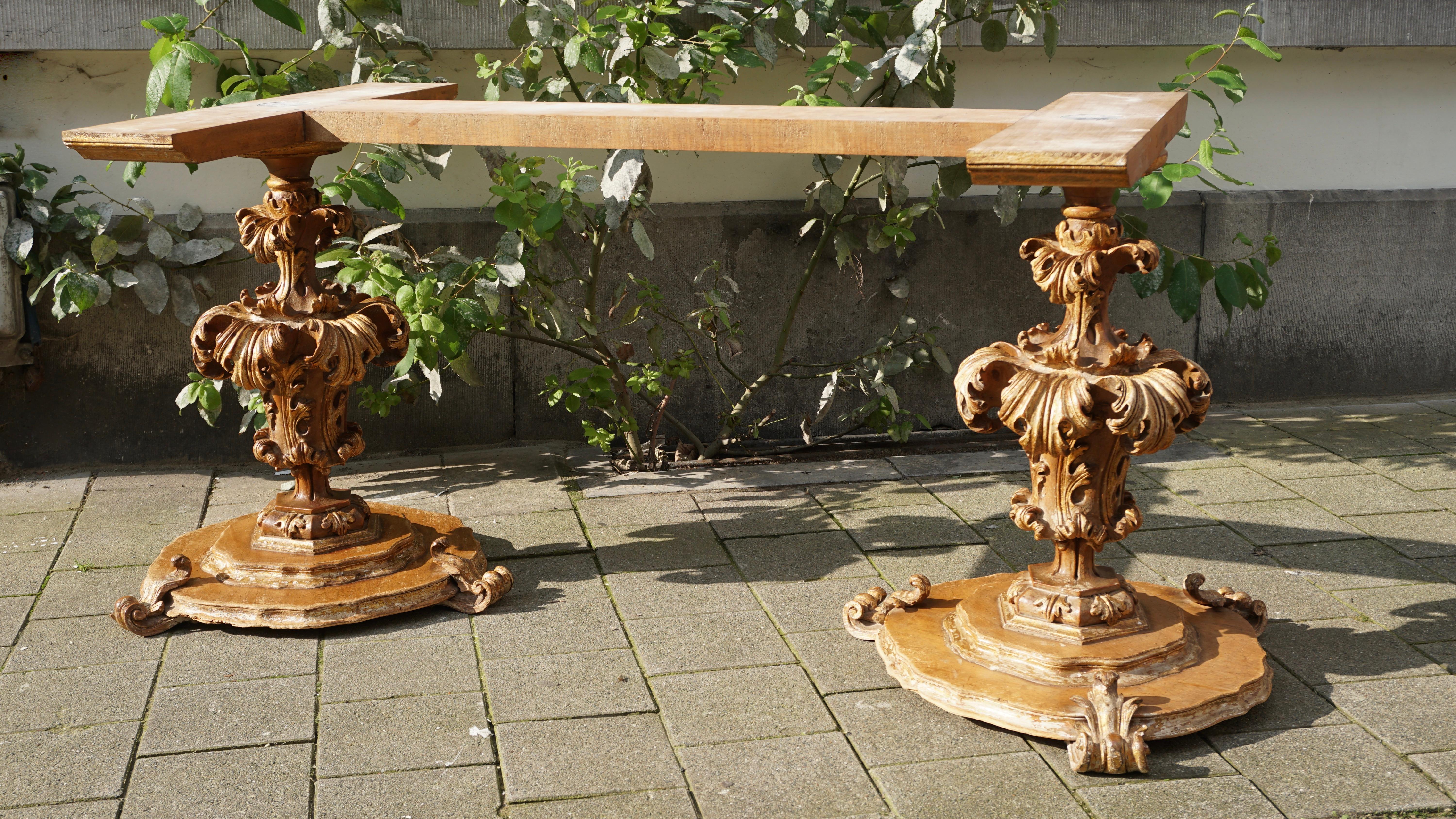 A extraordinary pair of table supports, in wood with layers of gold, and with deeply carved foliate leaves, on a ( later) base , with original wooden scrolls, also deeply carved and with the same layers of gold. Both pieces were part of an important