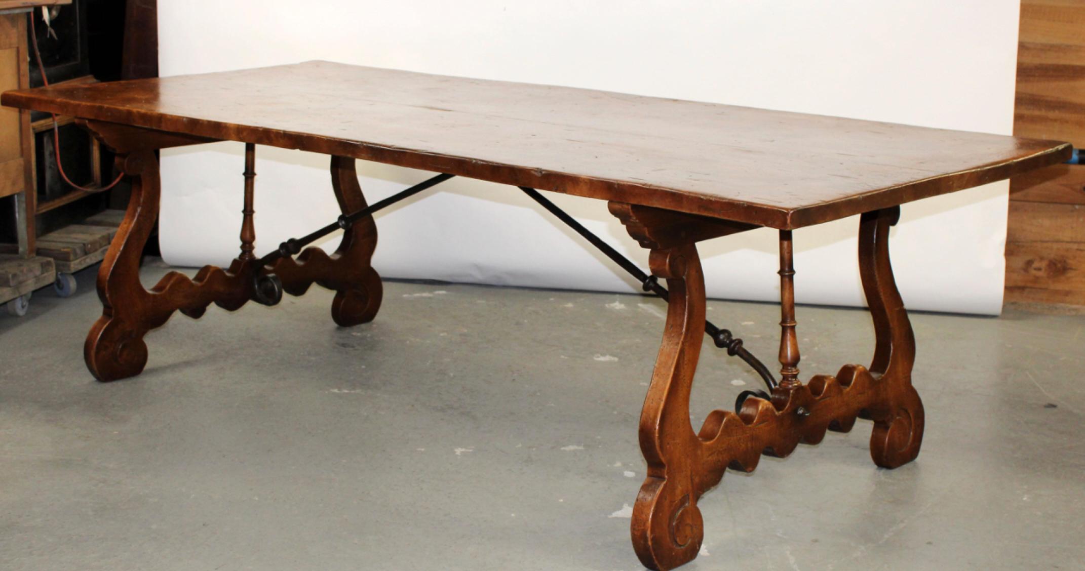 Extraordinary Italian Trestle Table. Typical Tuscany designed scalloped and turned Base with decorative Wrought Iron Supports. Rare Highly Figured Burled Elm Top made of two Planks with a rich color and deep patination. Made near Florence Italy 