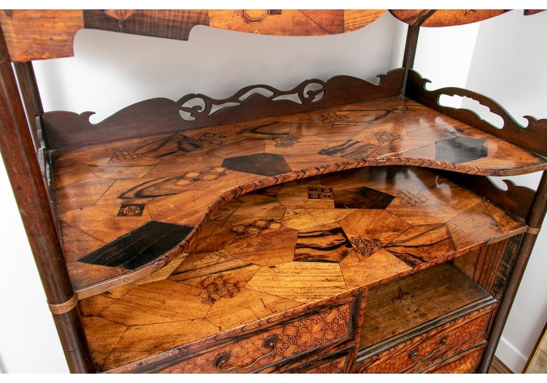 Una extraordinaria y meticulosa vitrina japonesa. Estilo en la cúspide del Art Nouveau/ Arts and Crafts con soportes curvilíneos de palisandro en los pisos superiores. Los soportes tienen bandas de cobre con decoración foliada. Los niveles con