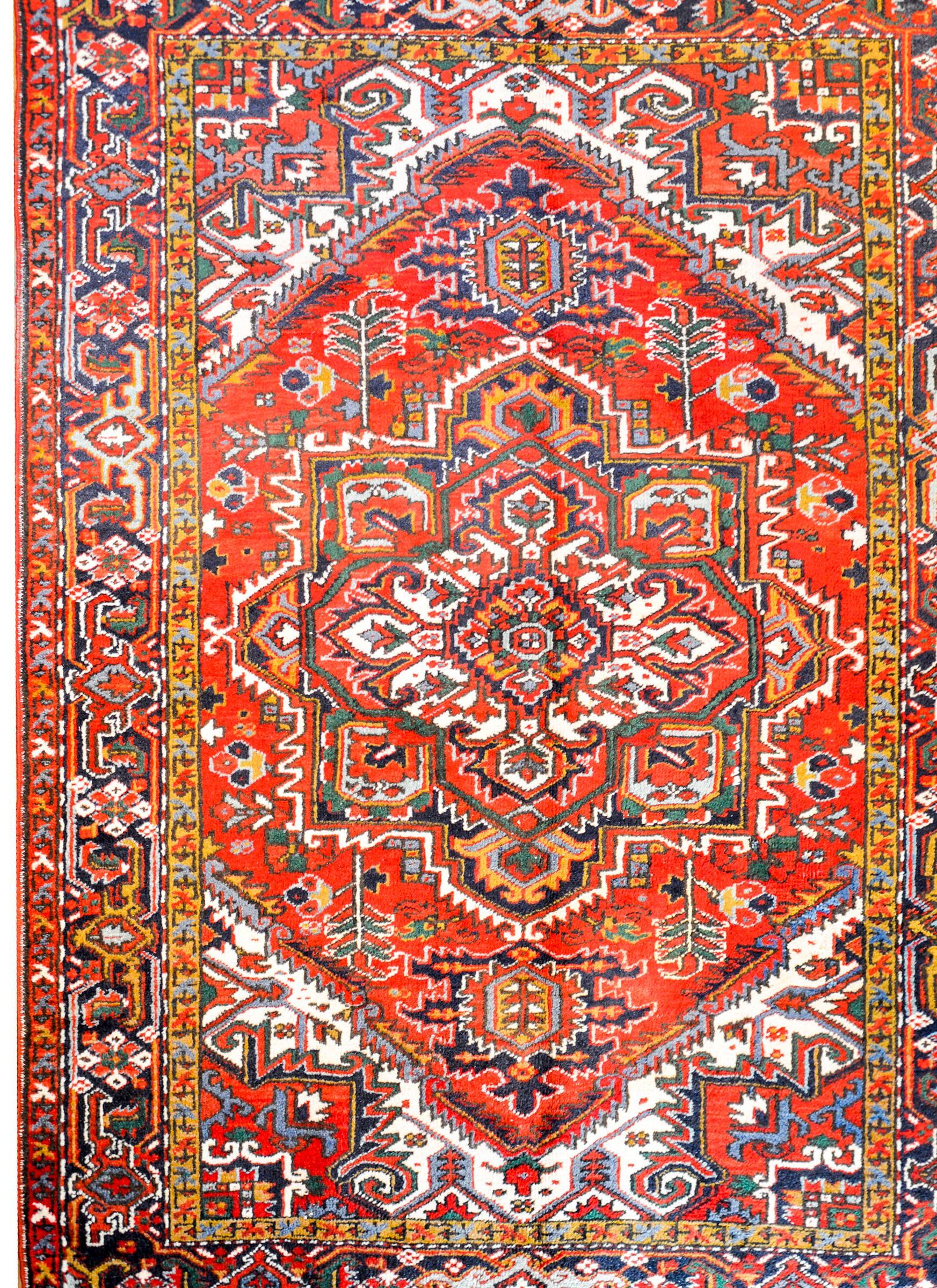 An extraordinary mid-20th century Persian Heriz rug with a fantastic large central eight-lobed floral medallion woven in myriad colors including crimson, indigo, green, gold, white, and coral colored vegetable dyed wool. The border is complex, with