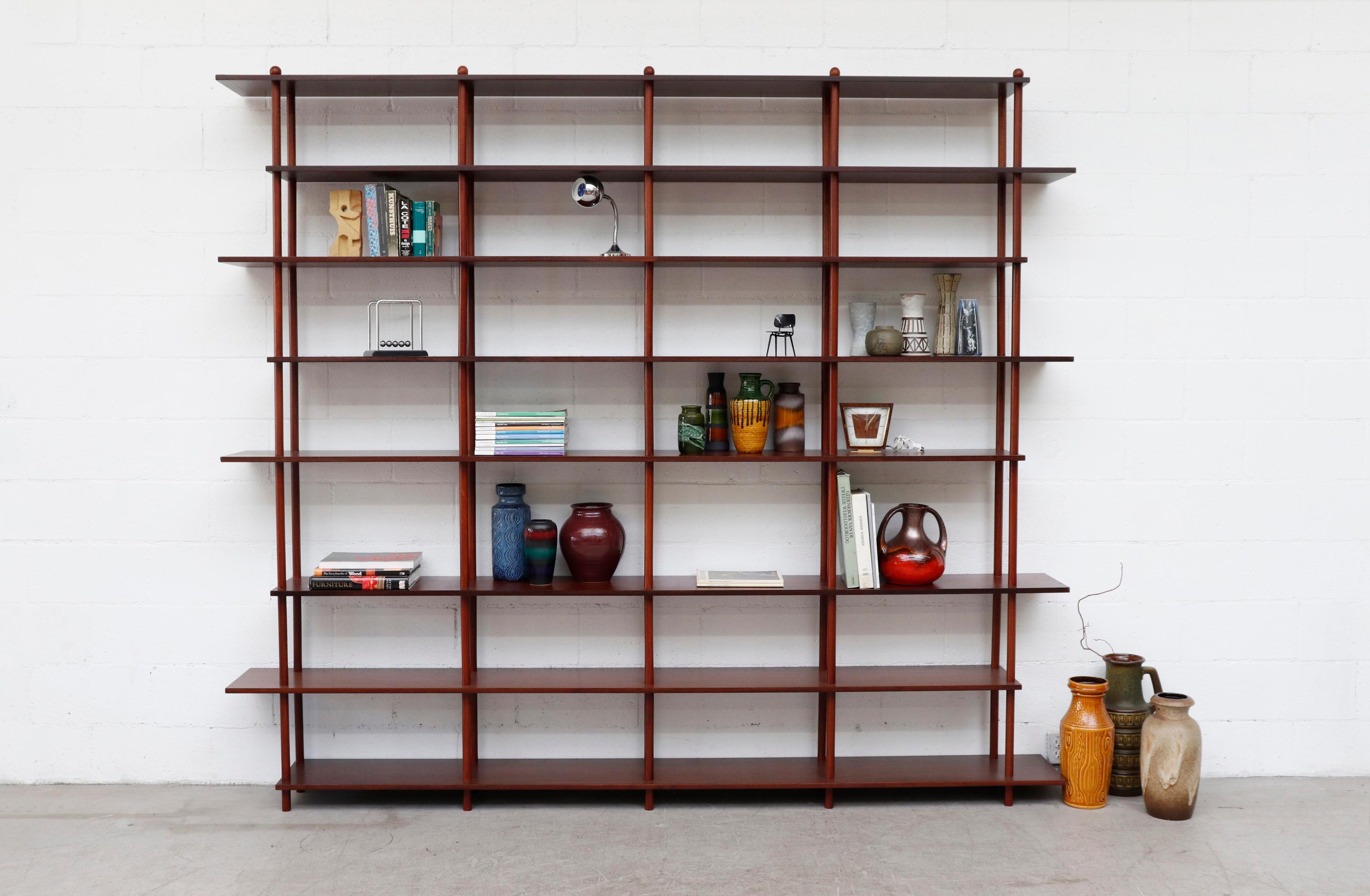 Mid-Century Modernist extra large 4 section stick shelf with dark mahogany tone shelves and posts. Can rearrange spacing and overhanging shelves to your needs. Lightly refinished in otherwise original condition with some shelves showing previous