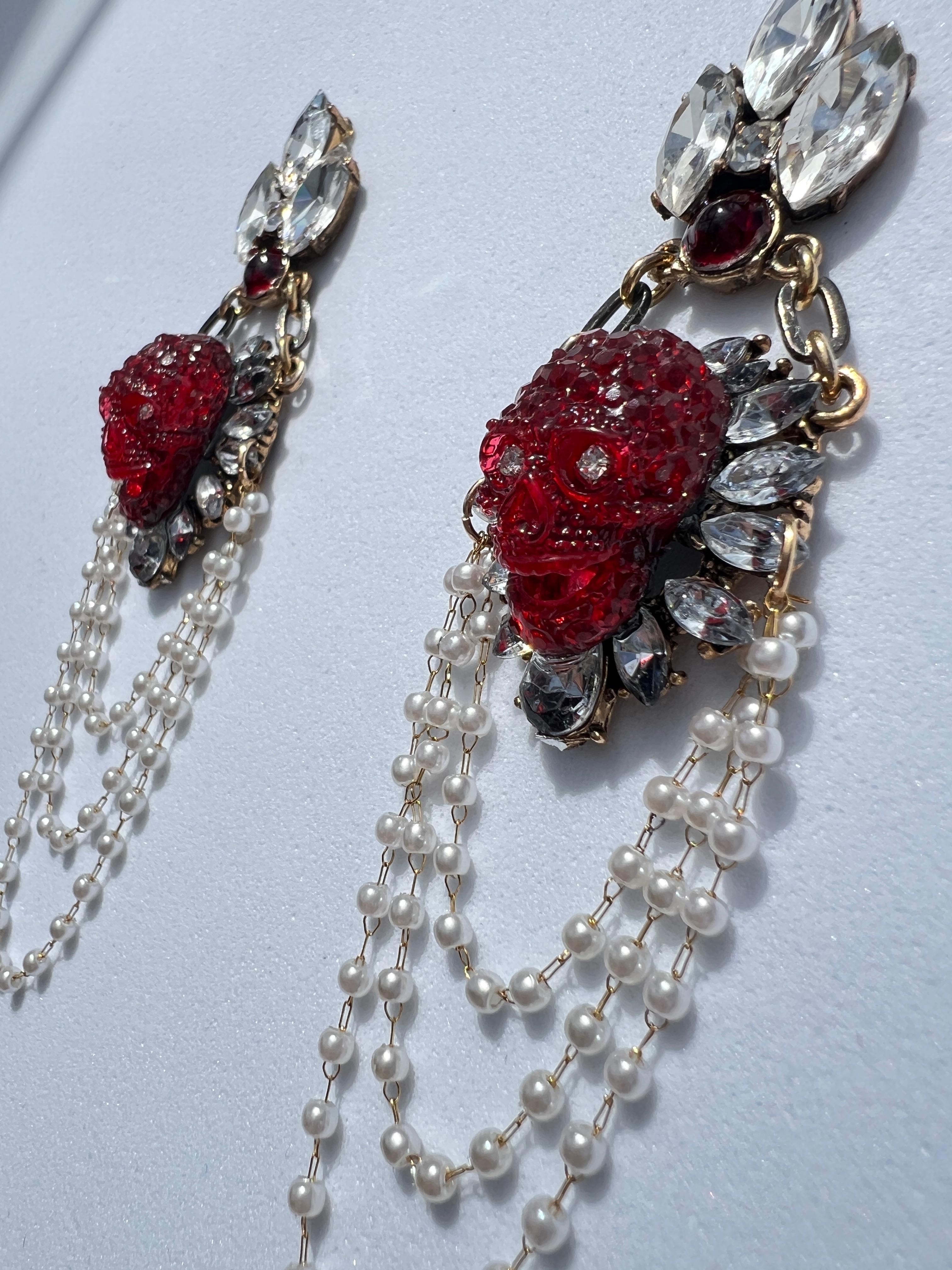 These one-of-a-kind, unique earrings are truly a masterpiece—there is only one pair, never to be repeated. With every movement, they dangle and shimmer, embedded with radiant crystals that catch the light. At the center of each earring is a striking