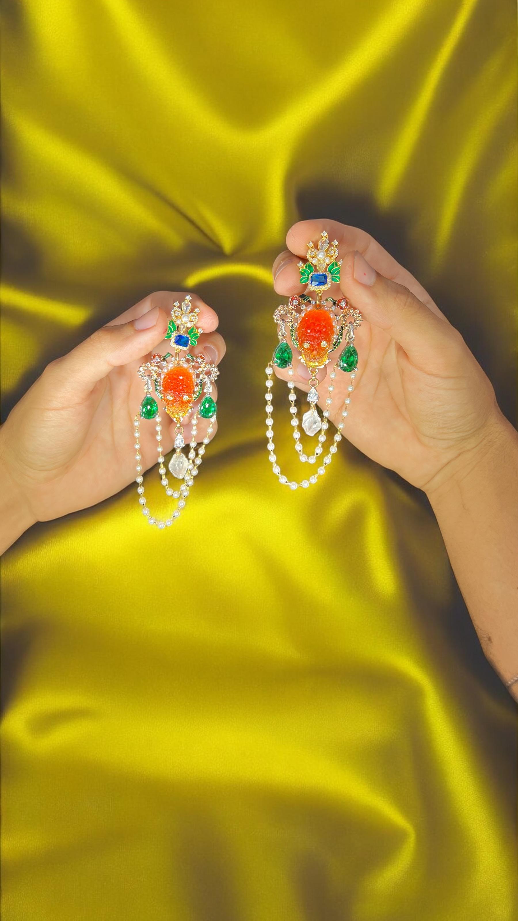 This one-of-a-kind pair of earrings is a true celebration of tropical elegance. Featuring vibrant green enamel leaves and flowers, they shimmer with radiant Swarovski crystals that catch the light beautifully. At the center of each earring sits a