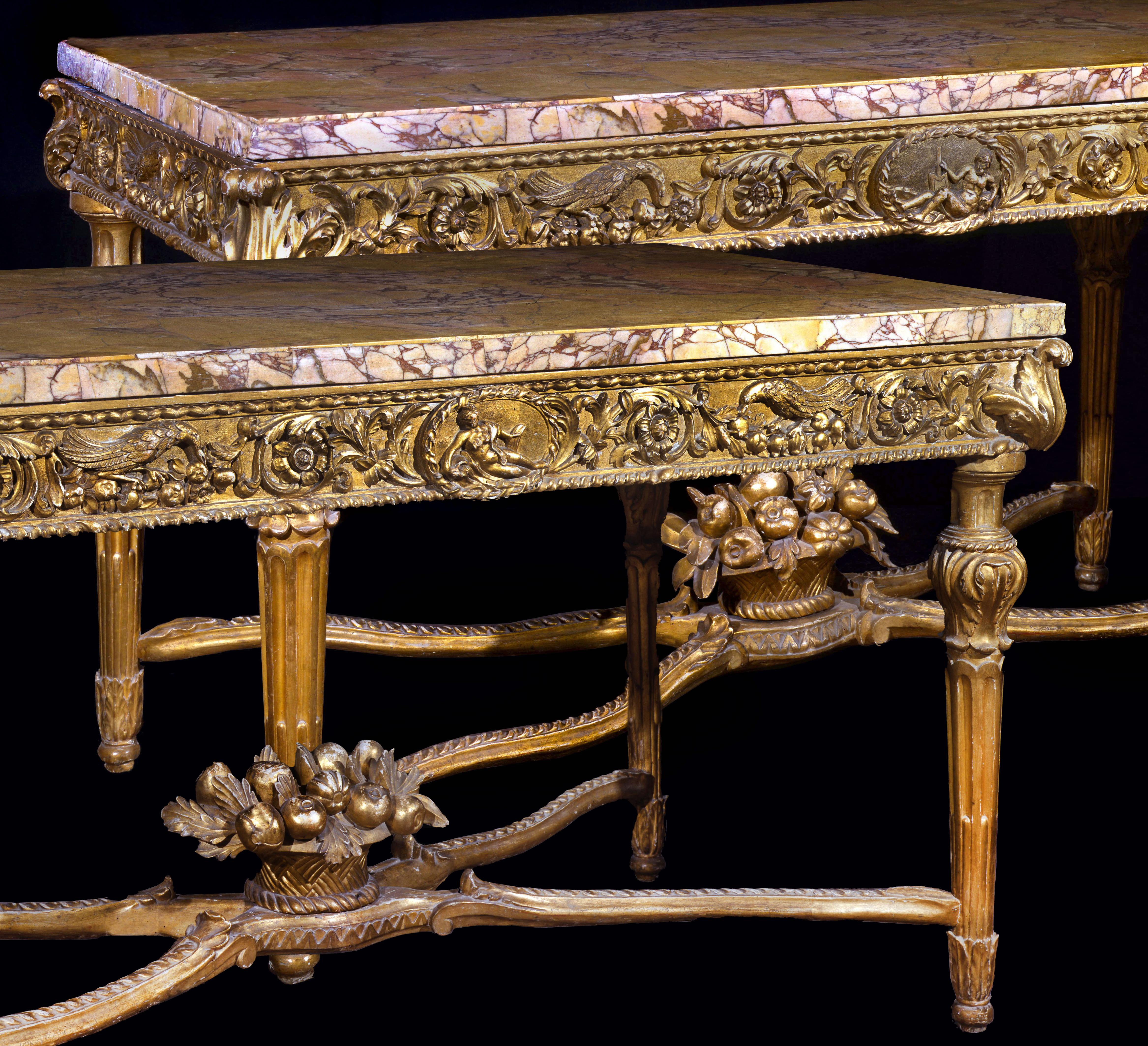 A very fine and important pair of Italian carved gilt-wood console tables, Roman, circa 1770
Each with a rectangular back, yellow and white marble top, above a frieze centered by a roundel, one with a recumbent male figure the other with a female