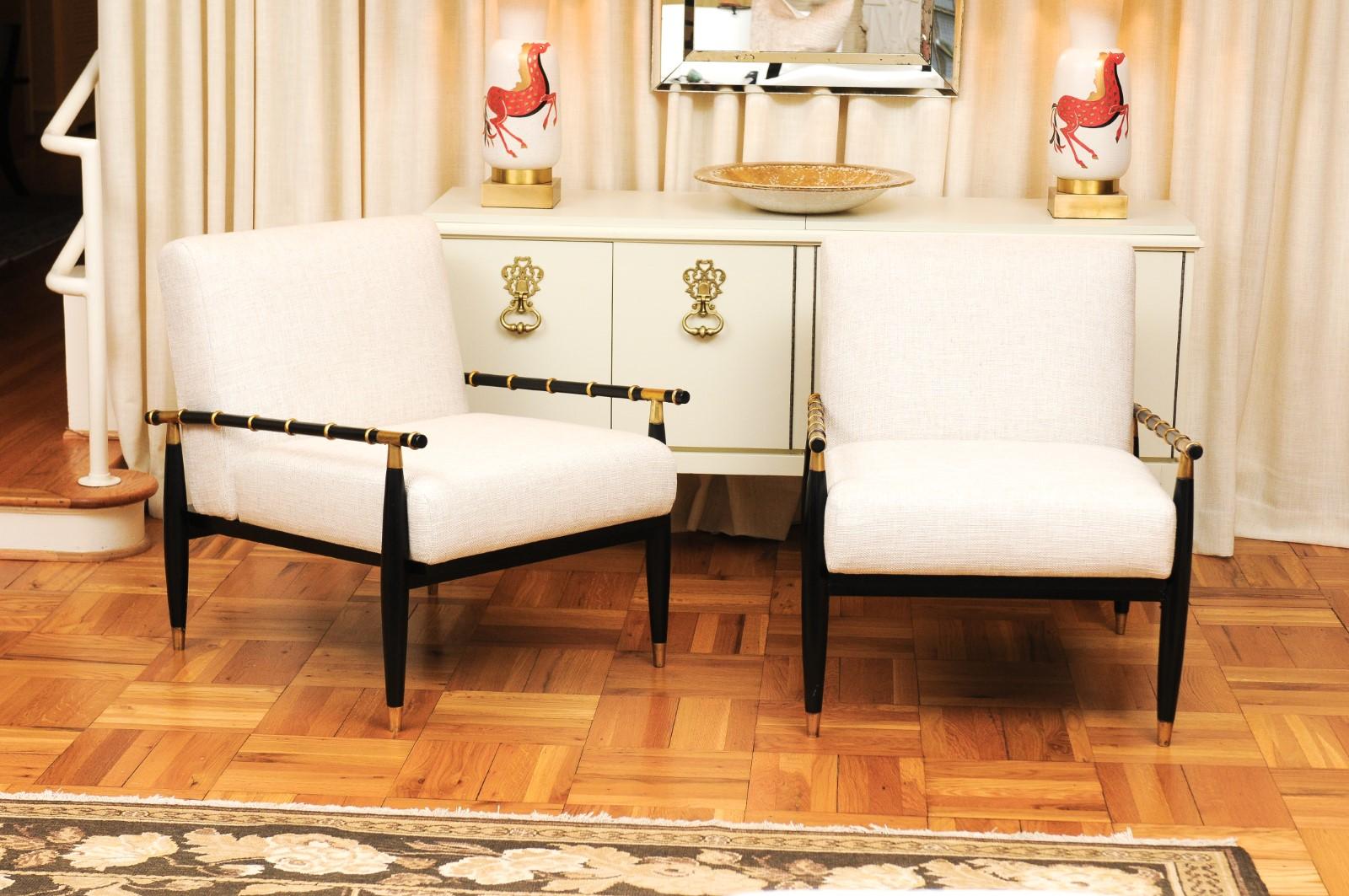 An exquisite meticulously restored pair of lounge chairs in the style of Tommi Parzinger, circa 1965. Sleek Mahogany frame with slender faux-bamboo arms. Accents and details in golf-leaf and solid brass. Exceptional design and craftsmanship.