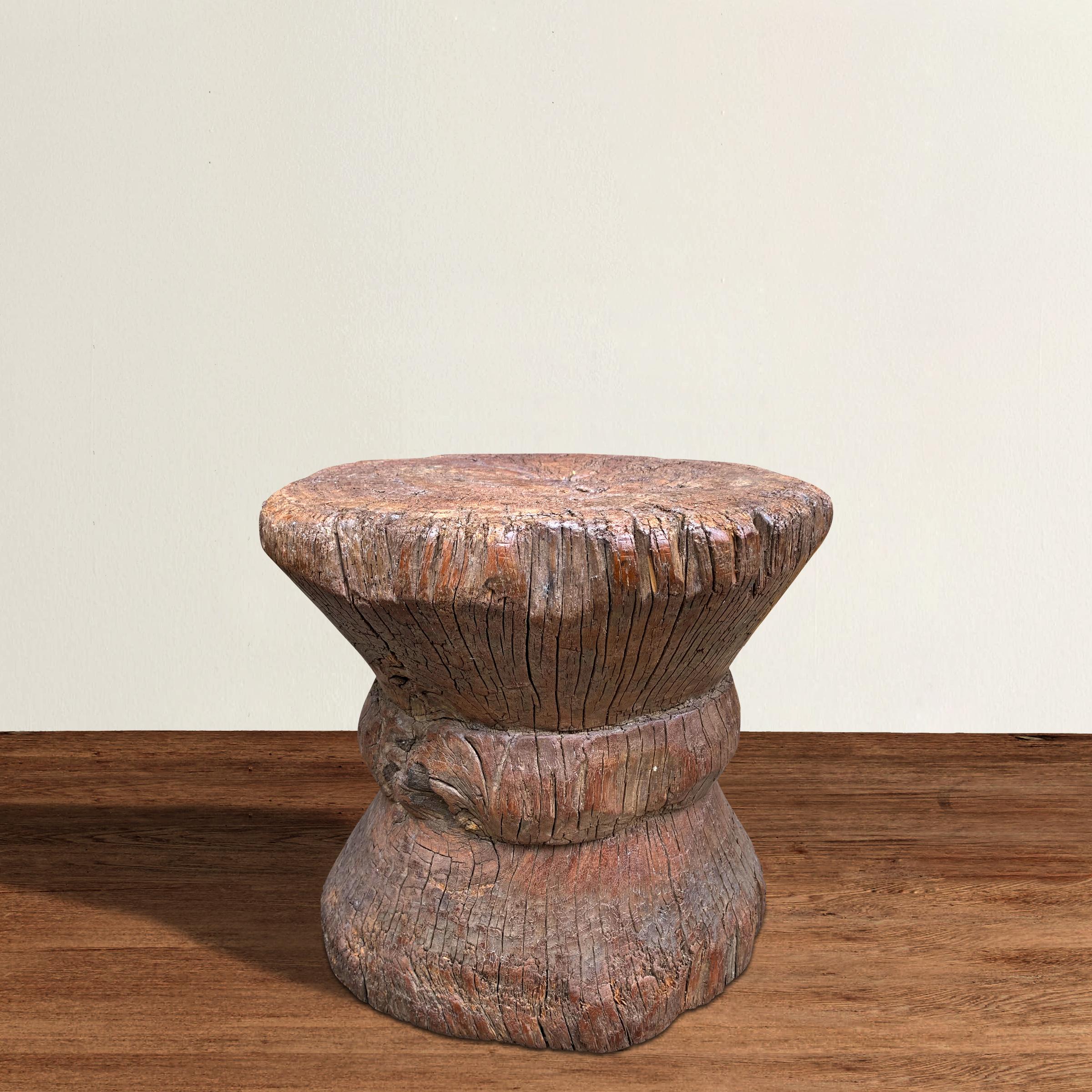 An extraordinary 19th century or earlier primitive carved wood stool or side table with a wonderful hour-glass form. A natural imperfection in the tree trunk adds a bit of wabi-sabi interest on the back side, along with an old iron strap repair.