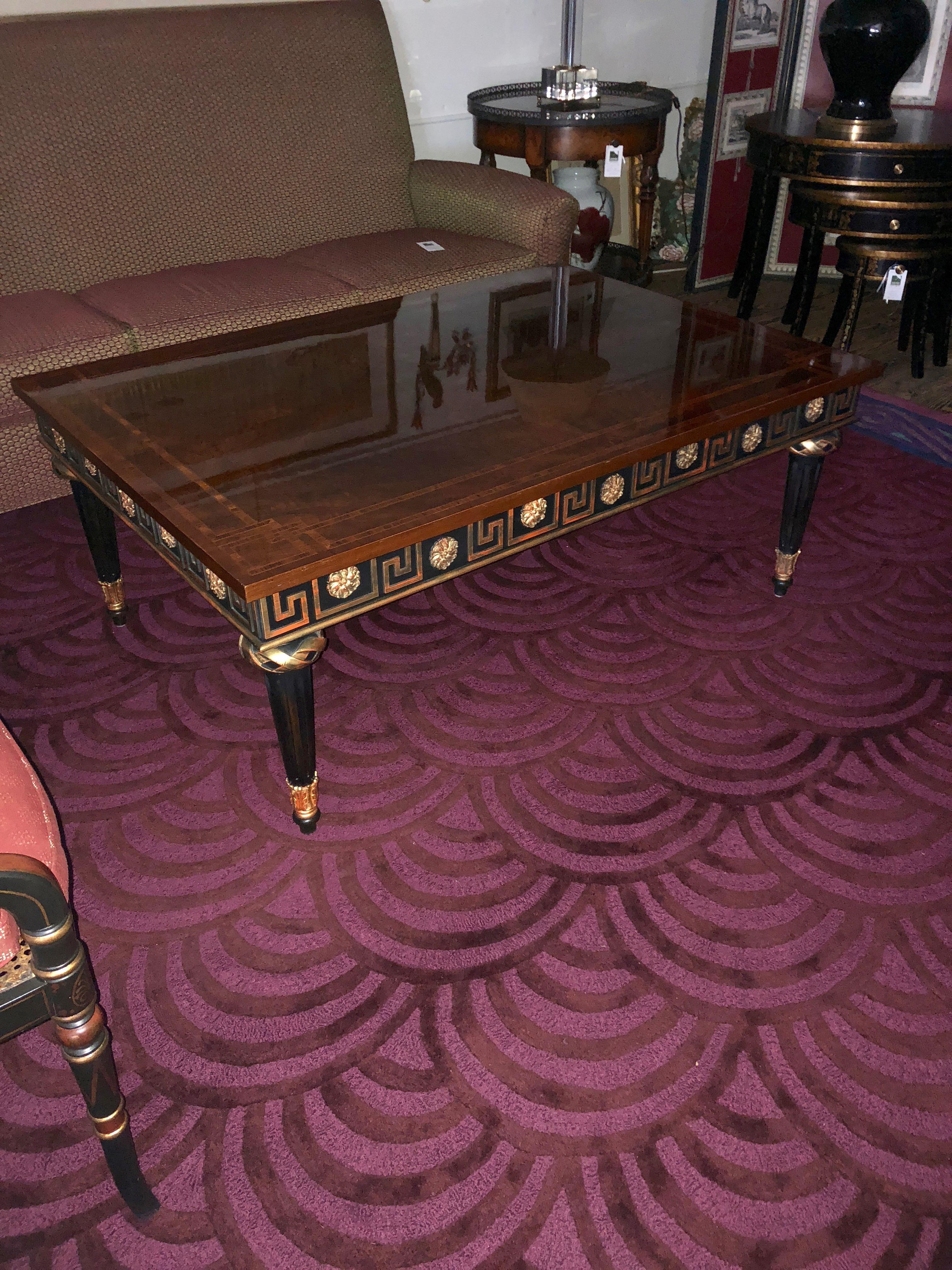 A sublimely rich Regency style bookmatched flame mahogany coffee table by John Widdicomb having magnificent satinwood inlay on top and ebonized apron and legs with gilded Greek key motife and fancy embellishments.