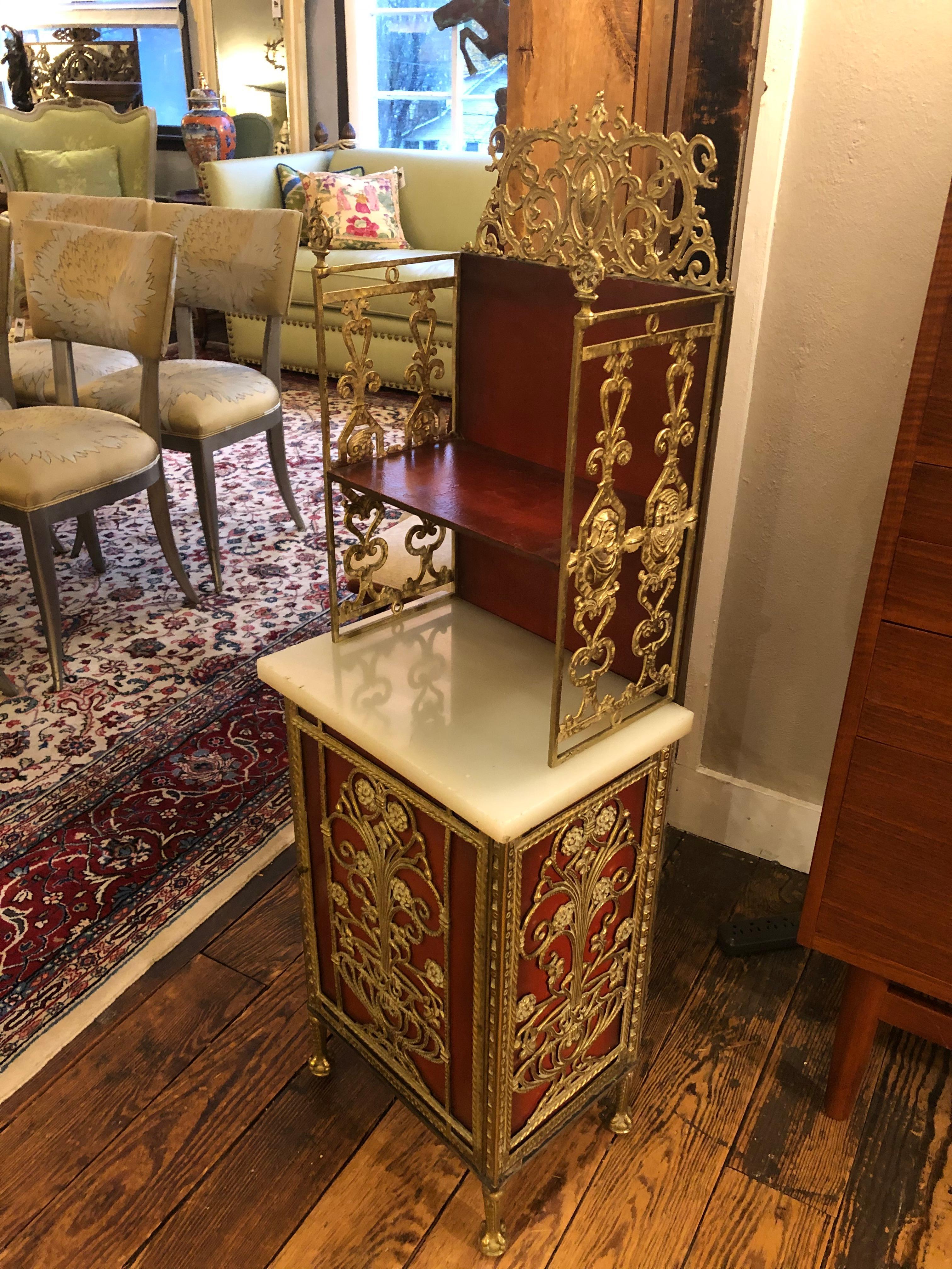 A rare gorgeous gem of a narrow elongated hall cabinet having ornate metal work over red metal structure, thick white onyx slab surface, one exterior shelf, and a door that opens to reveal storage inside. The interior also has two little metal doors