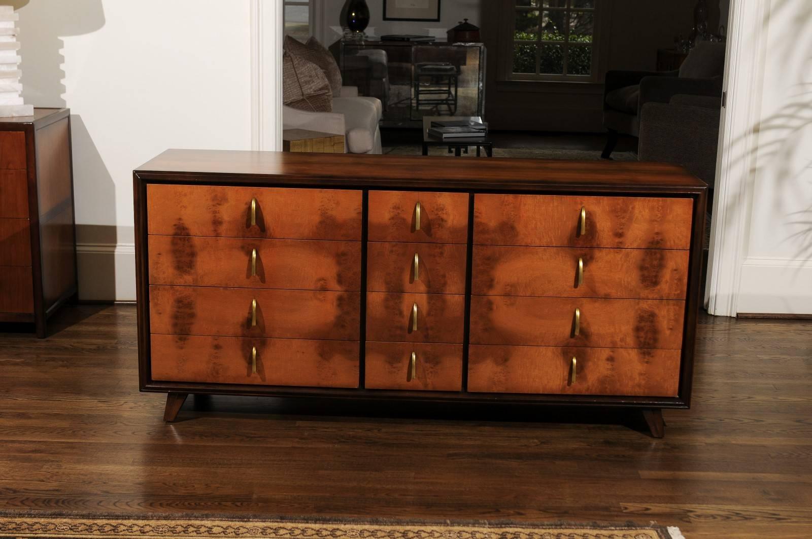 An exquisite 12 drawer chest by John Stuart, circa 1960. Superbly crafted solid black walnut case construction with drawer fronts veneered in bookmatched elm. Simple solid brass Art Deco influenced hardware accent the case. Stunning design and