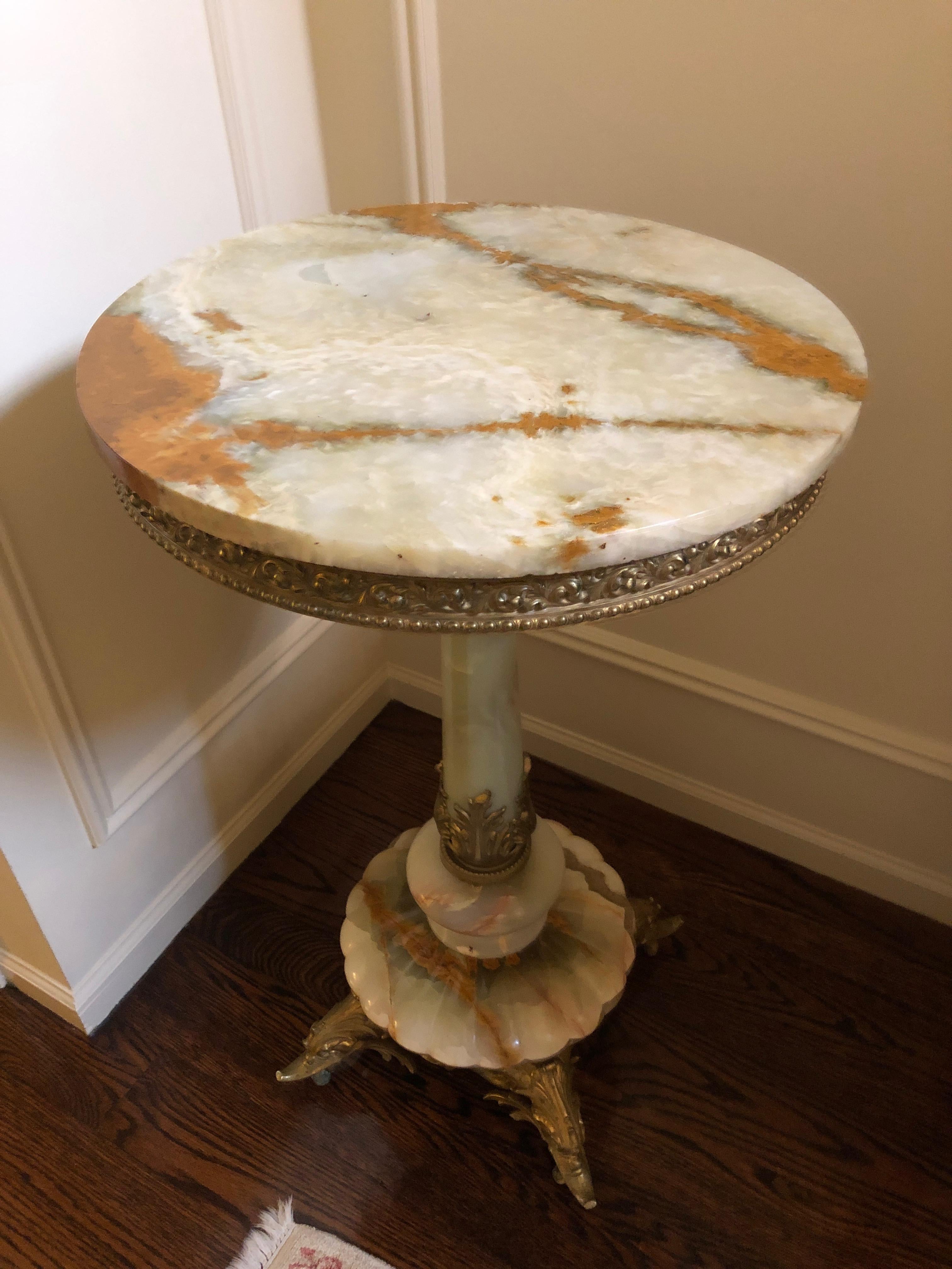 A superb and elegant French Empire style cast gilt brass and magnificent onyx circular pedestal side table having gorgeous coloration, ornate dragon or dolphin motife feet, and scalloped base.  A show stopper!