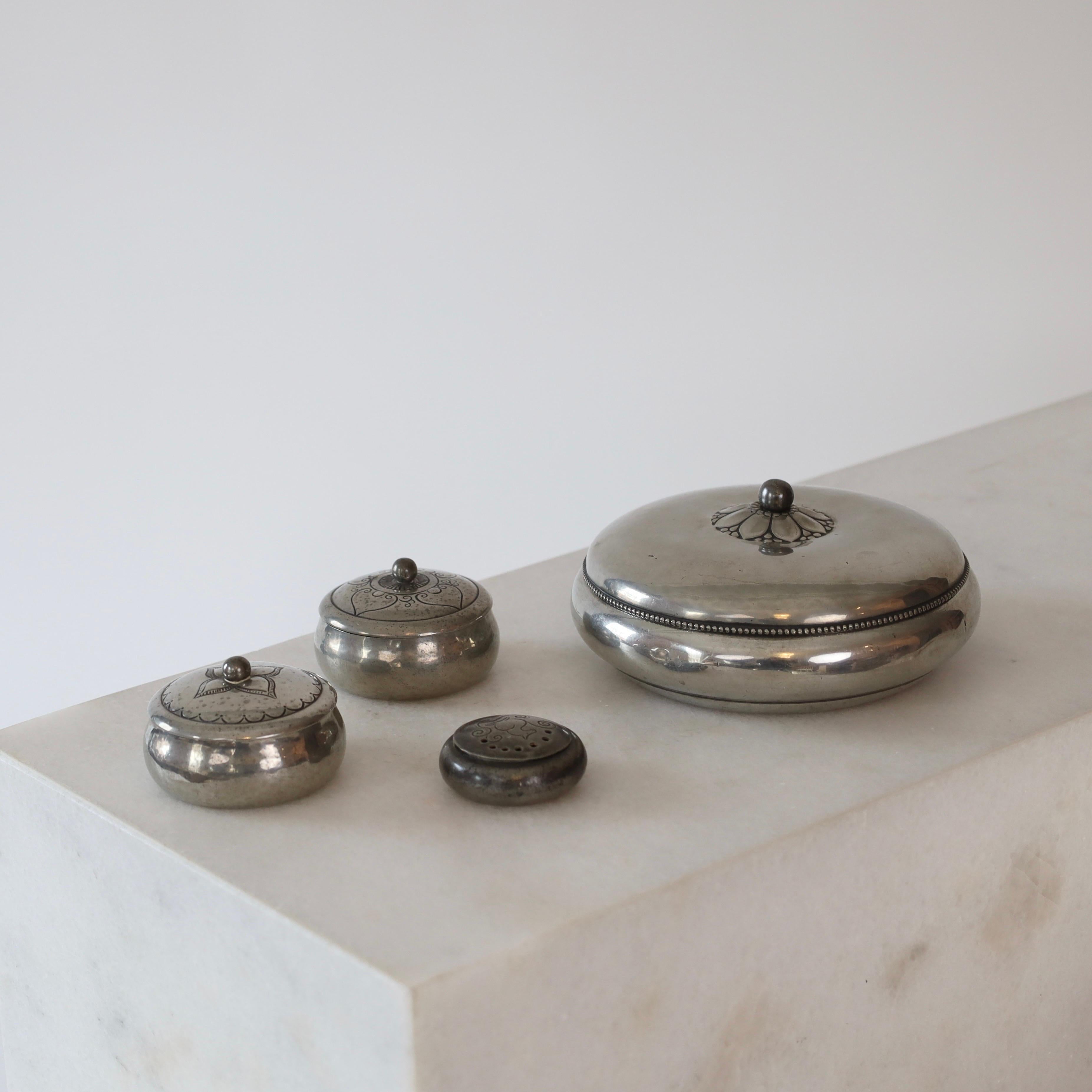 An extraordinary set of 4 lidded round pewter box designed by Just Andersen in the early 1920s. One larger and two small round boxes with lids ornaments and one tiny scent box. It is a rare find ready for a beautiful spot.

* A quartet of round