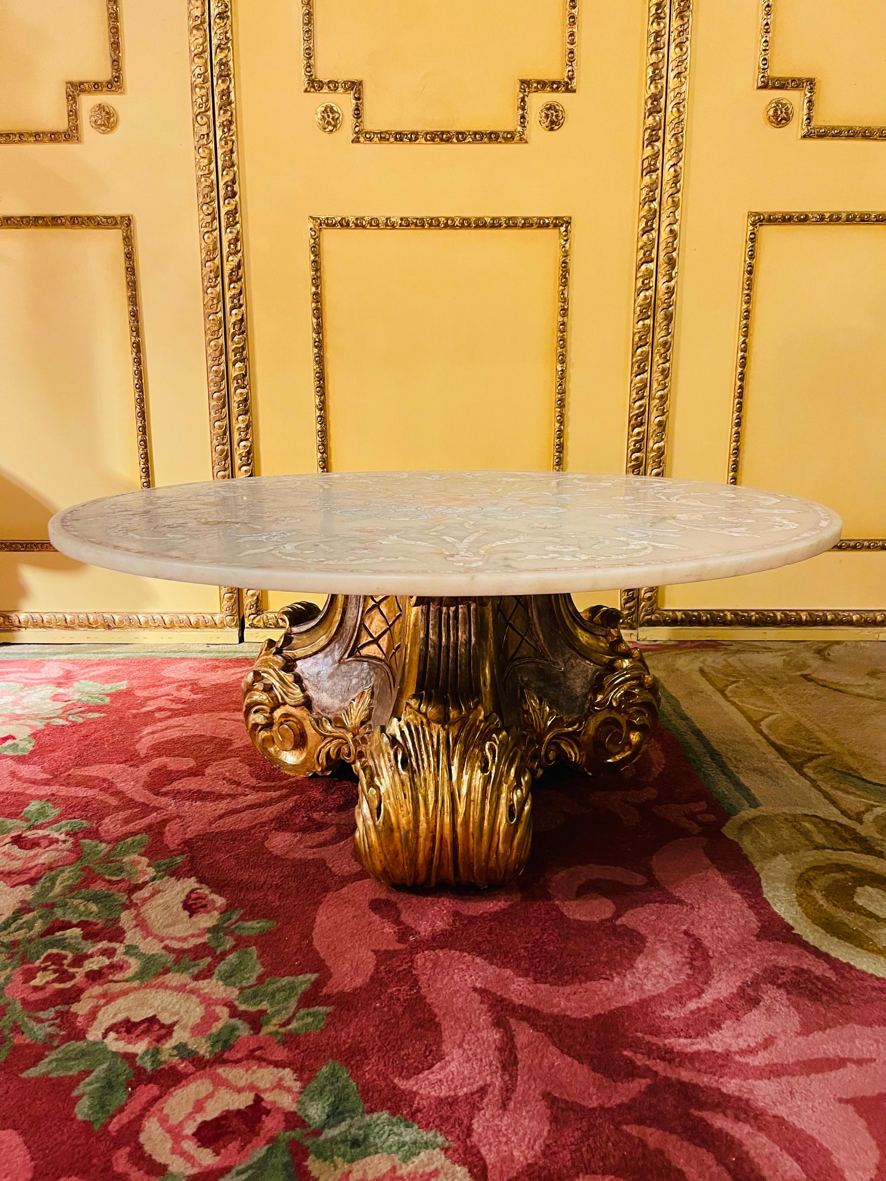 Extraordinary splendid Italian designer coffee table, gold with marble top.

Large round marble slab with hand-inlaid marble inlays (Pietra Dura) supported by a solid, splendid wooden base, finely carved and gilded.

Very high quality processed.