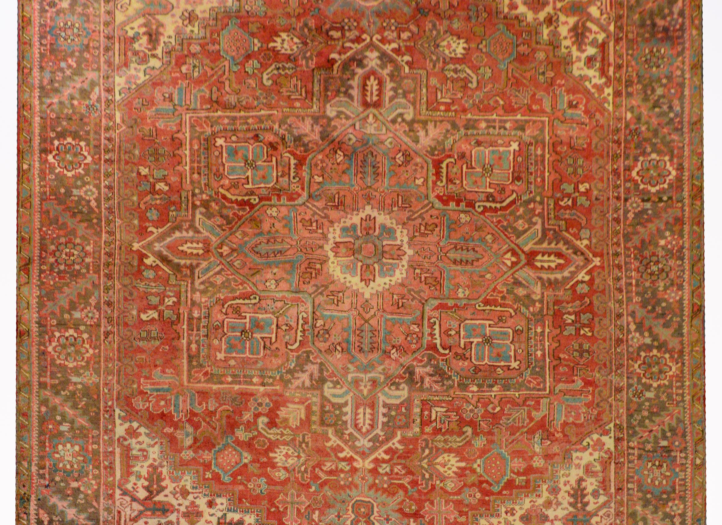 An extraordinary mid-20th century Persian Heriz rug with a large eight-sided floral patterned medallion on a field of flowers surrounded by a fantastic border woven with a large-scale floral and leaf pattern, all woven in crimson, orange, indigo,