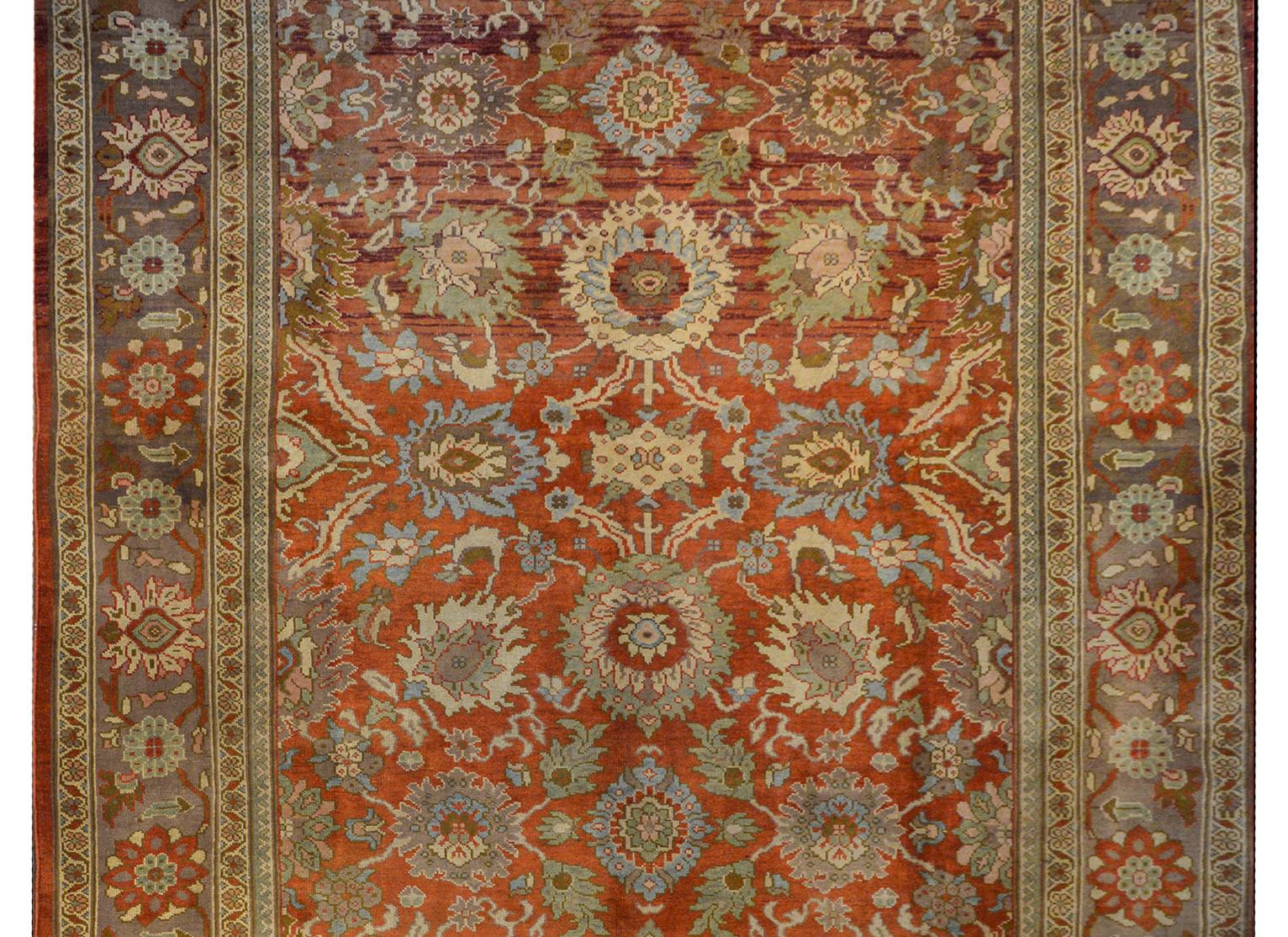 An extraordinary 21st century Persian Sultanabad rug with a wonderful bold large scale floral pattern woven in light indigo, pale yellow, pale green, olive green, and cream, all on an abrash rust colored background. The border is fantastic with a