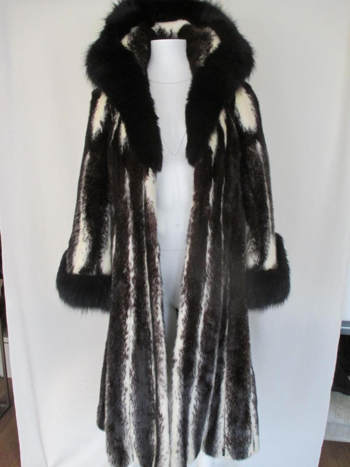 This exclusive coat is made from soft quality cross mink / kohinoor fur, Saga Nerz,  trimmed with black fox at the collar and sleeves and a huge collar.
It has 2 velvet pockets and 4 closing hooks.
The sleeves are flared.
In good pre- owned