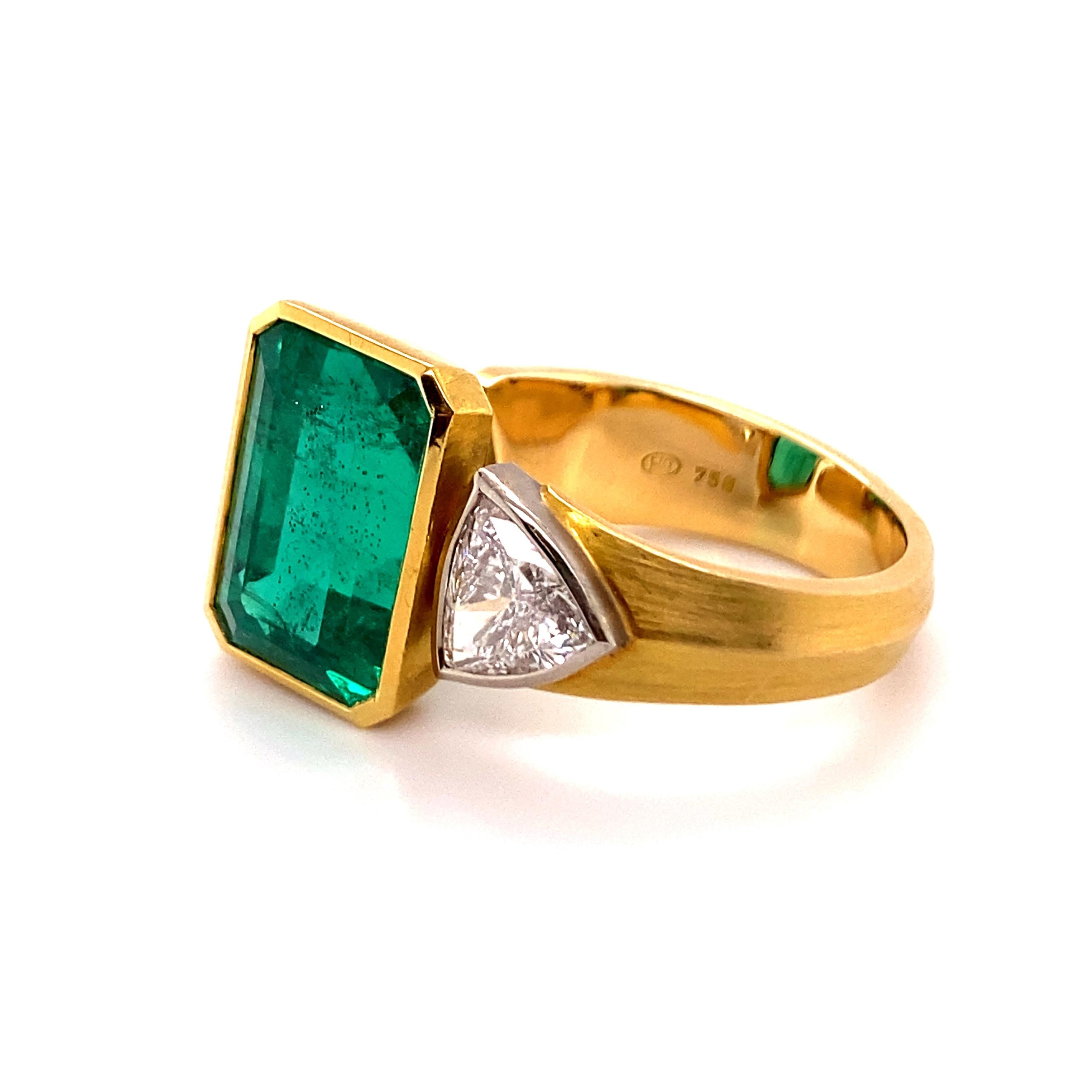 El anillo está diseñado para que la piedra principal quede centrada entre los dos dedos al llevarlo. La fina esmeralda colombiana engastada en bisel, de aproximadamente 10,16 quilates, presenta una elegante talla escalonada alargada. La gema es de