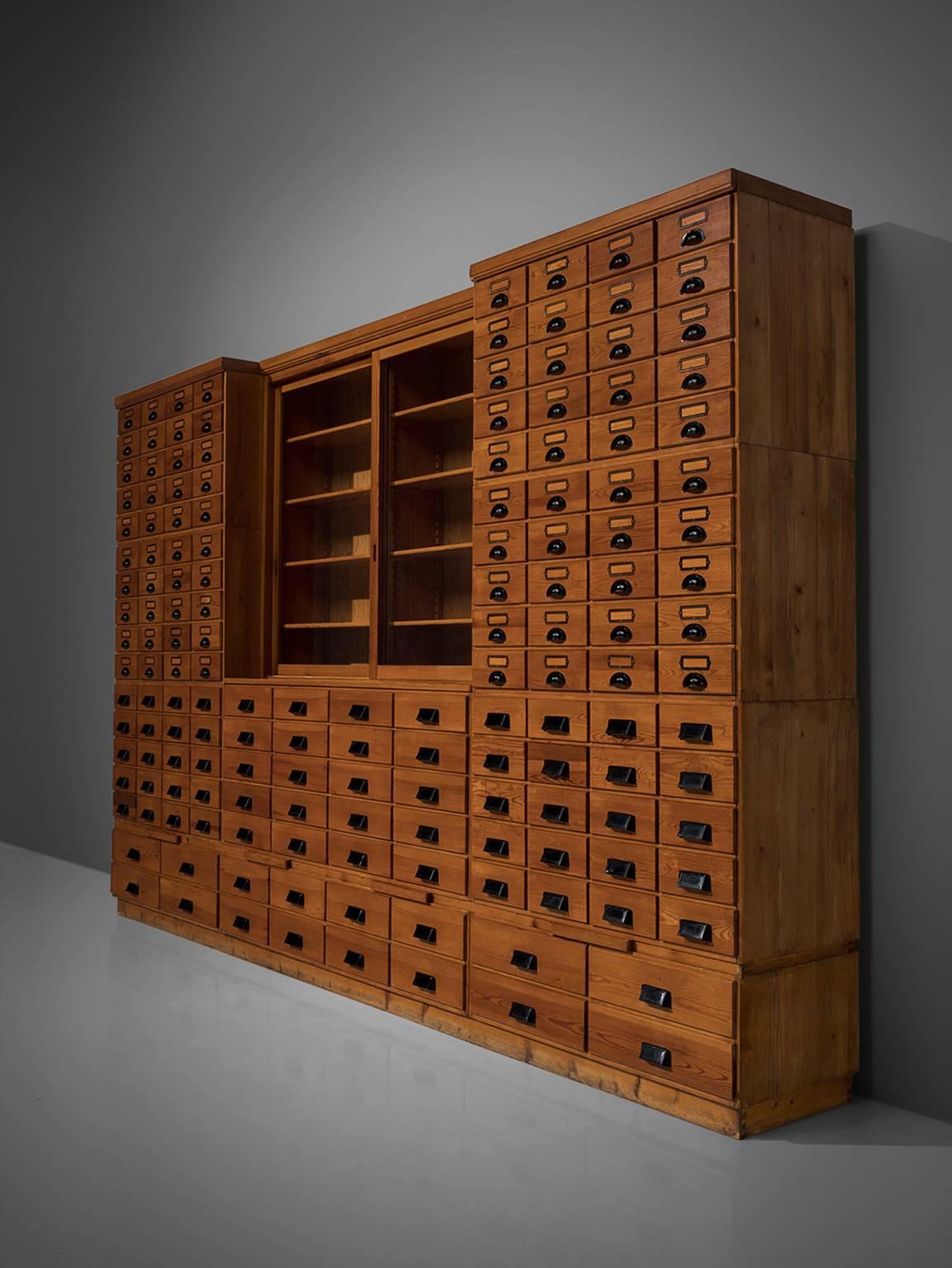 Schrank, aus Holz, Glas und Metall, Dänemark, 1950er Jahre.

Extrem große Apothekerkommode mit insgesamt 156 Schubladen! Dieses schöne Stück ist aus Rotholz gefertigt und besteht aus elf Elementen, die jeweils mit Schubladen in verschiedenen