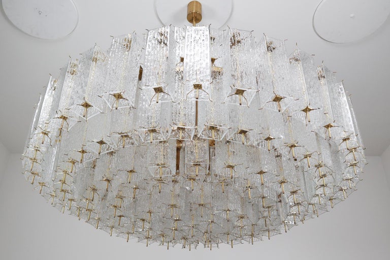 Wonderful and very heavy quality chandelier made in Europe, manufactured, circa 1960s. The chandelier has 28 (E27) sockets and holds numerous structured glass 'tubes' with a brass centre. The sheets beautifully refracting light. This chandelier will