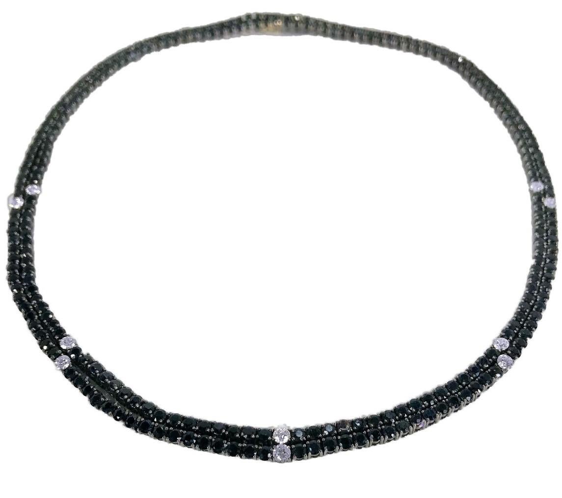 This striking necklace is comprised of a double strand of 2.5mm round faceted, extremely dark blue natural sapphires with a total approximate weight of 12.00ct. The double line is punctuated by four stations of diamonds positioned  at 1 3/4 inch