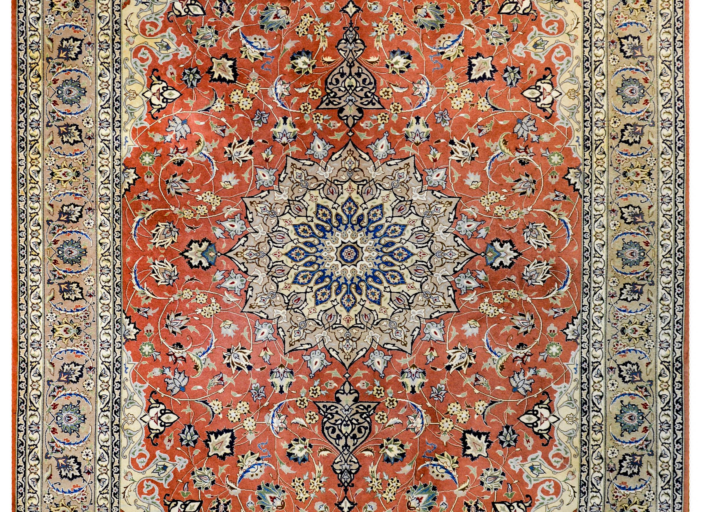 An extremely fine late 20th century Persian Tabriz with a mesmerizing pattern containing a large central multi-lobed medallion on a orange field of scrolling vines, leaves, and myriad blossoming flowers. The border is wonderful with a wide central