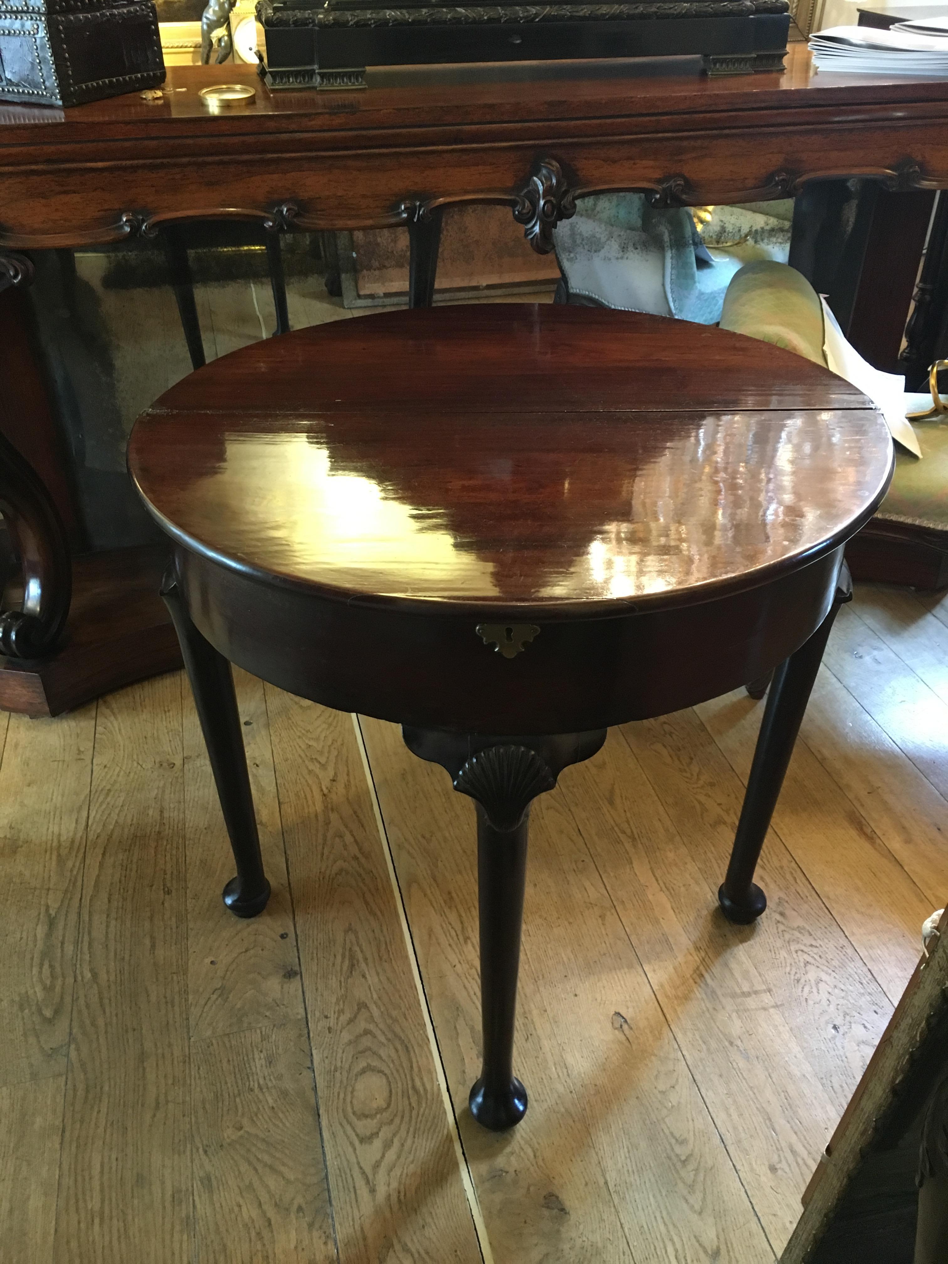 Extremely fine George II folding tea table. Opens out to round table excellent color and patination.
Carved shell detail to top of leg and concealed compartment with brass key plate.
circa 1750-1760

Measures: Height, 72 cm
Width, 76.5