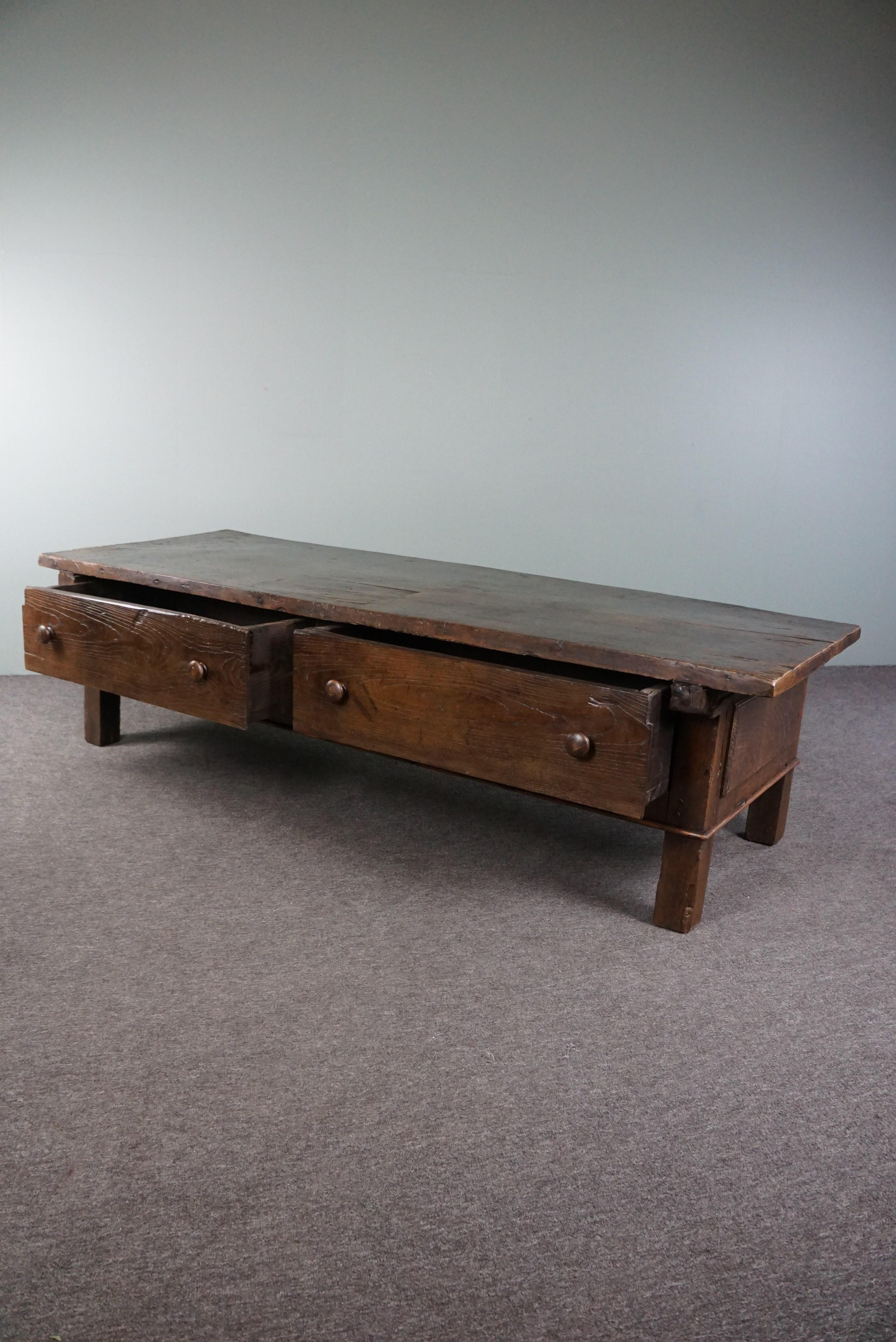 Offered is this antique coffee table with a single-piece tabletop originating from France. This exceptionally long antique French coffee table with a single-piece tabletop and two drawers is not just a piece of furniture; it's an heirloom soaked in