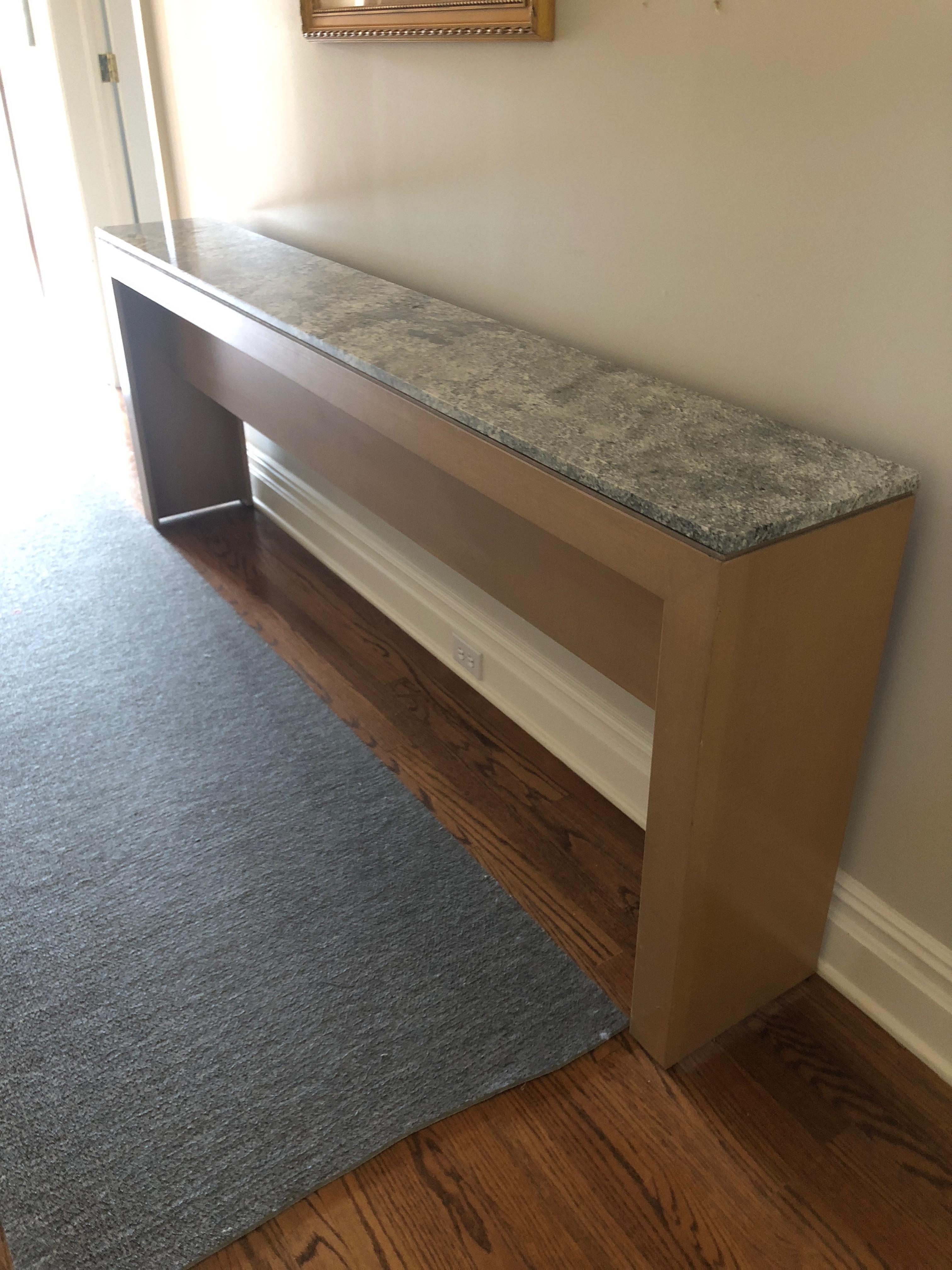 An extremely long custom contemporary console table having a light wood base with simple clean lines and a sleek grey and white marble top. Great for a hallway as the depth is narrow.