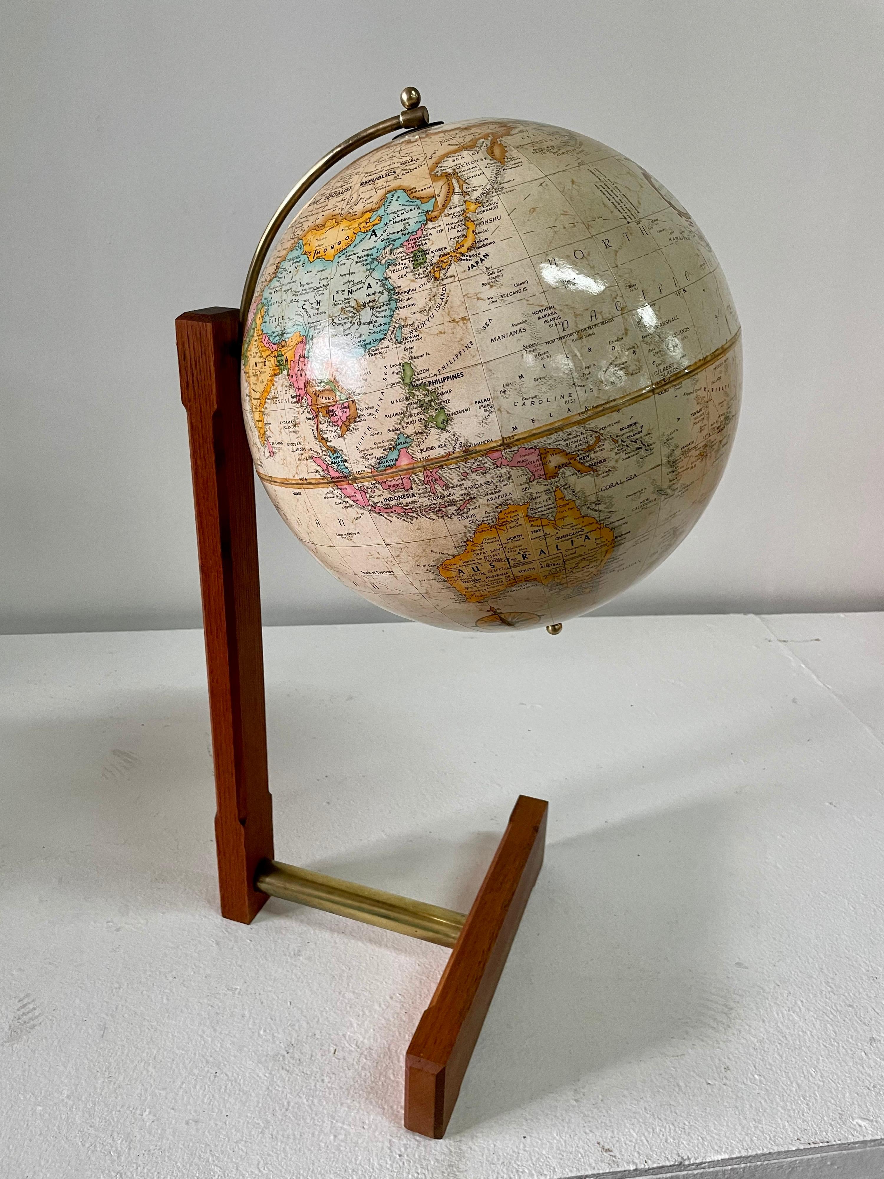Diese bodenhohe Weltkugel im Arts & Crafts-Stil wurde in den 1960er Jahren von der Firma Replogle hergestellt und steht auf einem sehr originellen freitragenden Sockel mit Messingstab und Teakholzrahmen. Der sehr saubere Globus mit einem Durchmesser