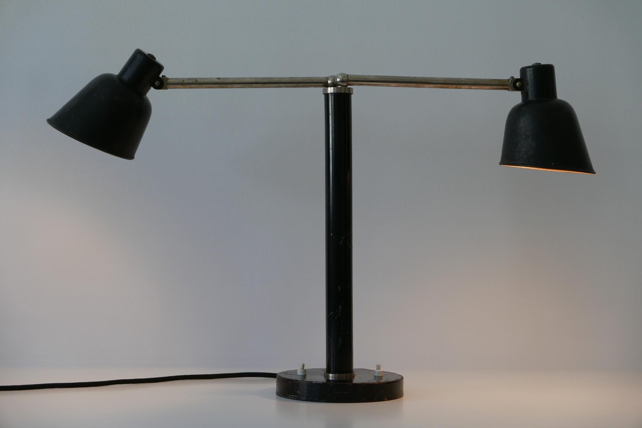 Extremely rare, two-armed Bauhaus / Modernist table lamp with adjustable arms and shades. Designed by Christian Dell for Bünte & Remmler (BuR), 1930s, Germany.

Executed in black enameled and partly nickel-plated metal, the lamp needs 2 x E27 Edison