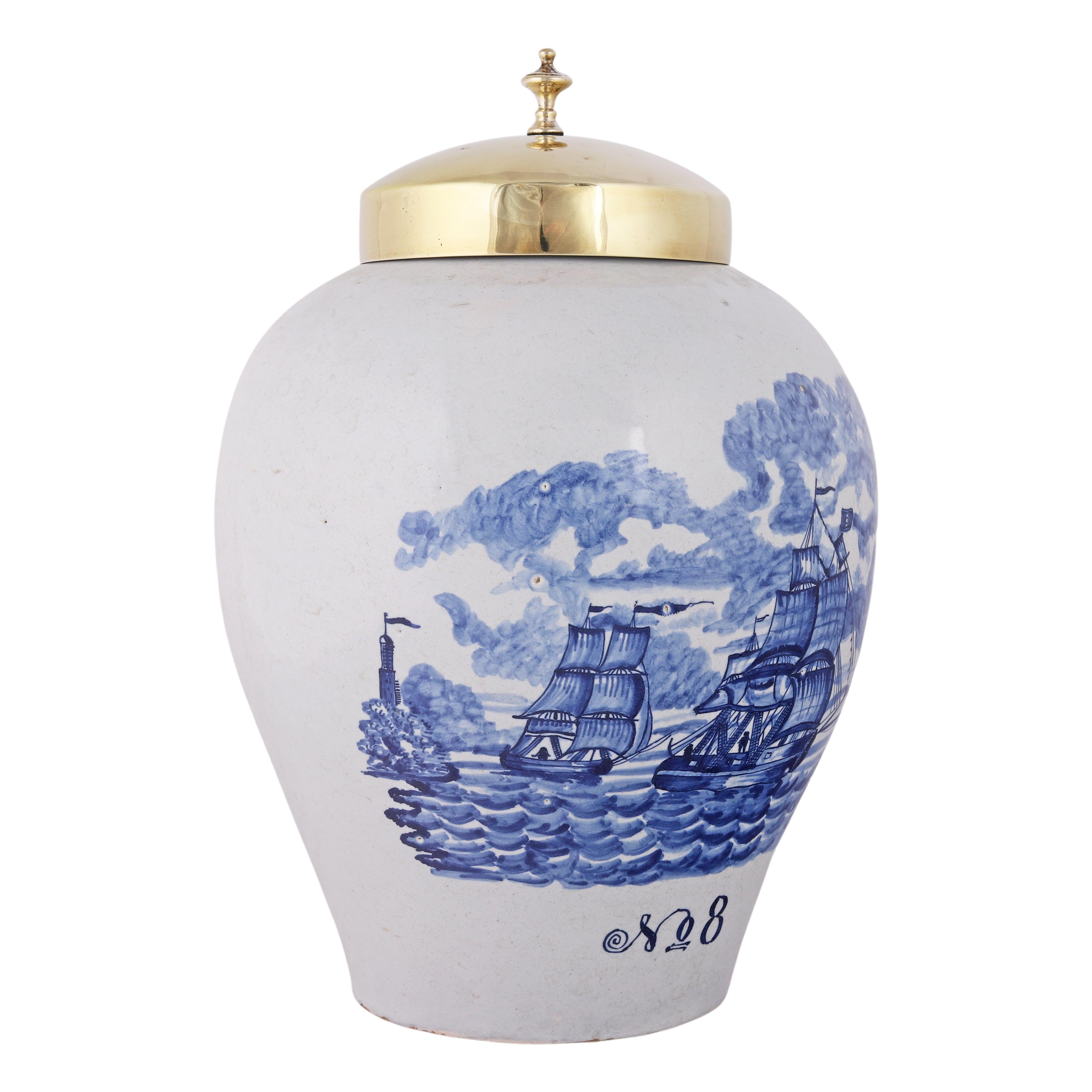 Delft
1760 – 1800
Taller: De Vergulde Bloempot (La maceta dorada)

Raro tarro azul y blanco para guardar tabaco, con tapa original de latón.
El tarro está decorado con una inusual escena de barcos mercantes en el mar. Esta escena naval fue