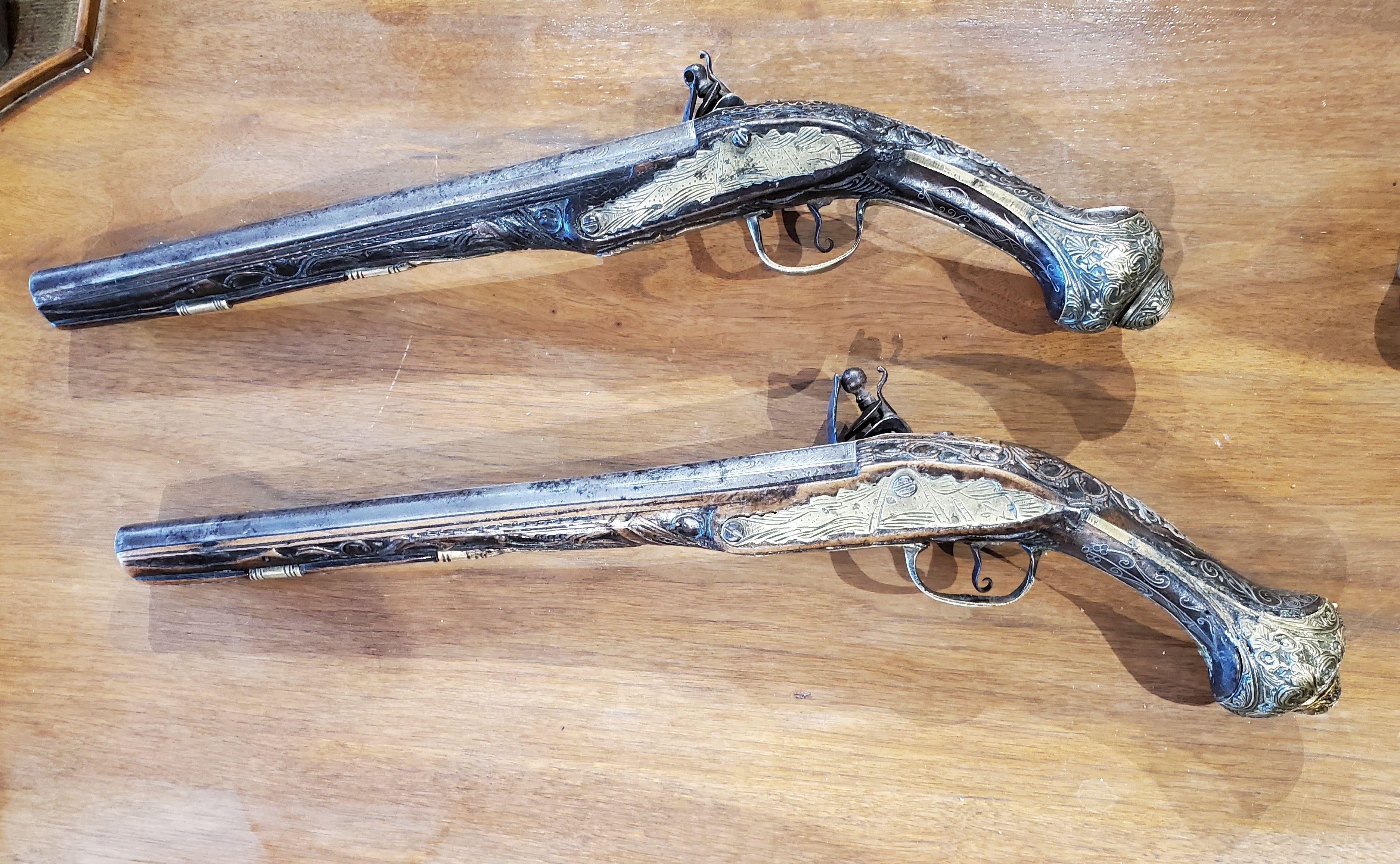 These extremely rare early 18th century flintlock pistols showcase extraordinary craftsmanship with carved walnut stocks inlaid with silver and brass. Intricately etched steel barrels and retaining the original goatskin holster. 

Made in Turkey