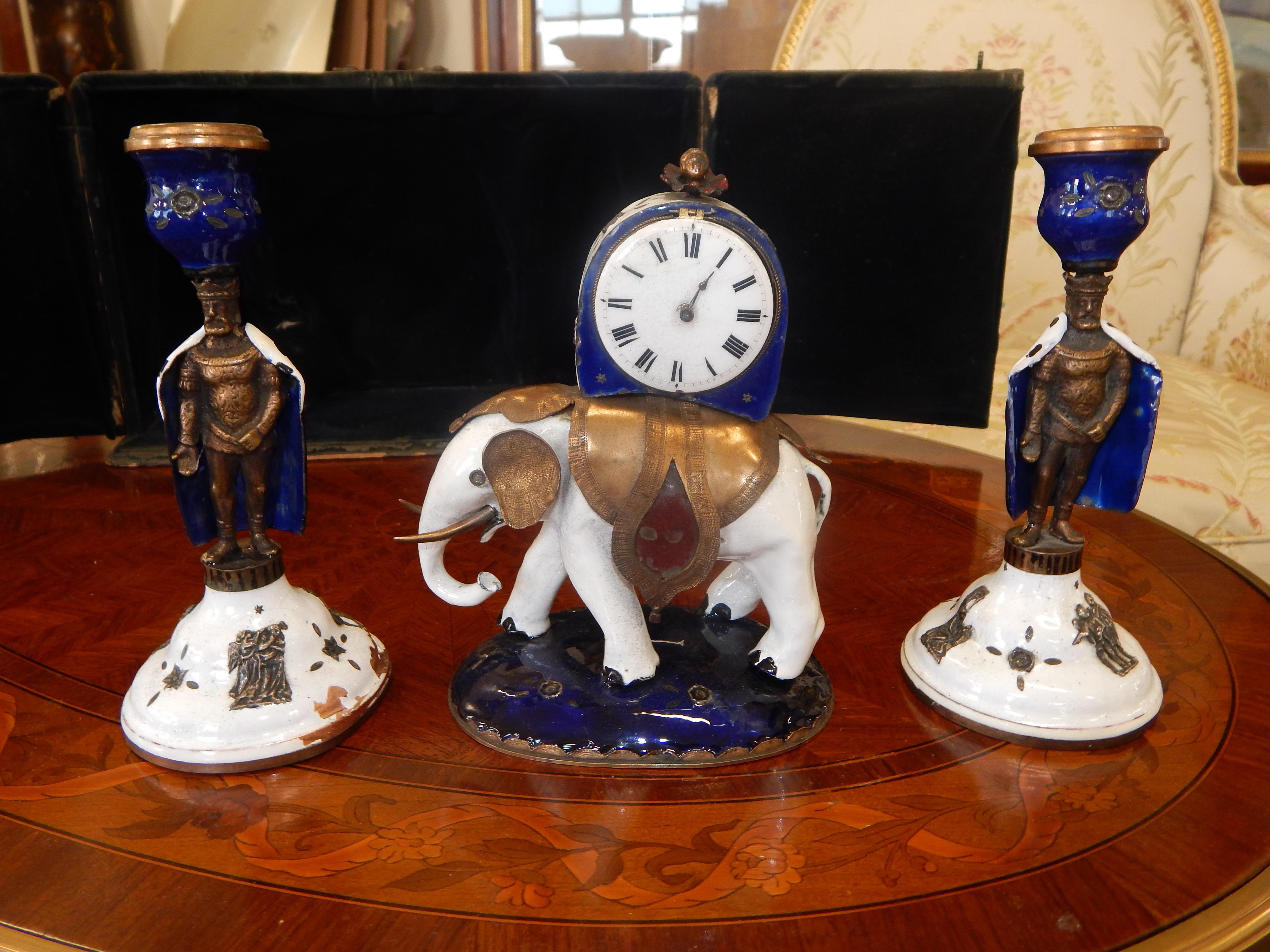A rare enameled three-piece elephant clock set with figures.

It comes with the original travel case, so this was made for elite clientele.

The clock is in the form of an elephant, with the clock sitting on top.

The candlesticks look like