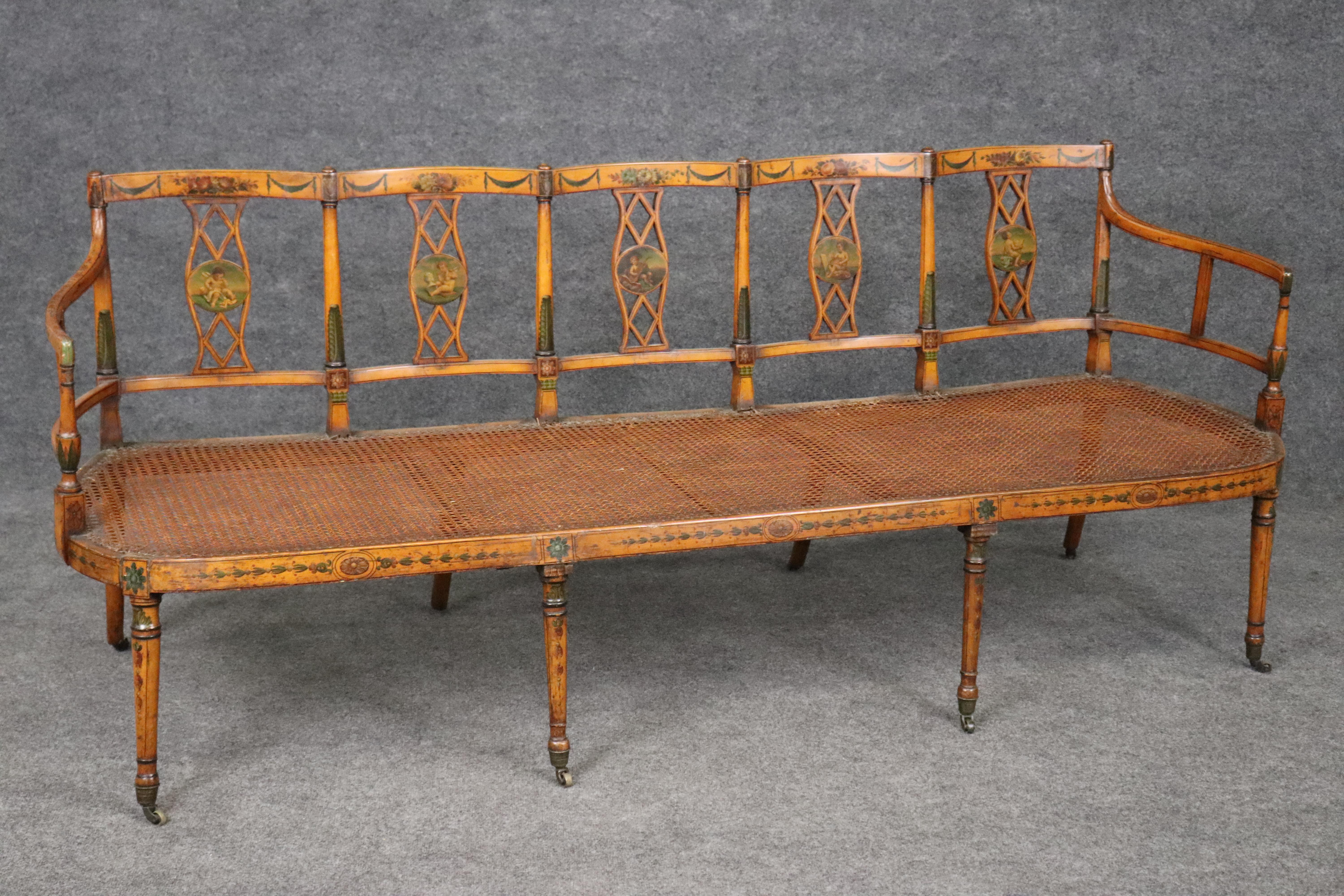 This is a superb and extremely rare five-seater Adams paint decorated settee in satinwood with fantastic hand-painted details of cherubs and figures and floral motif. The piece dates to the late 1880s era and is English and will show signs of age