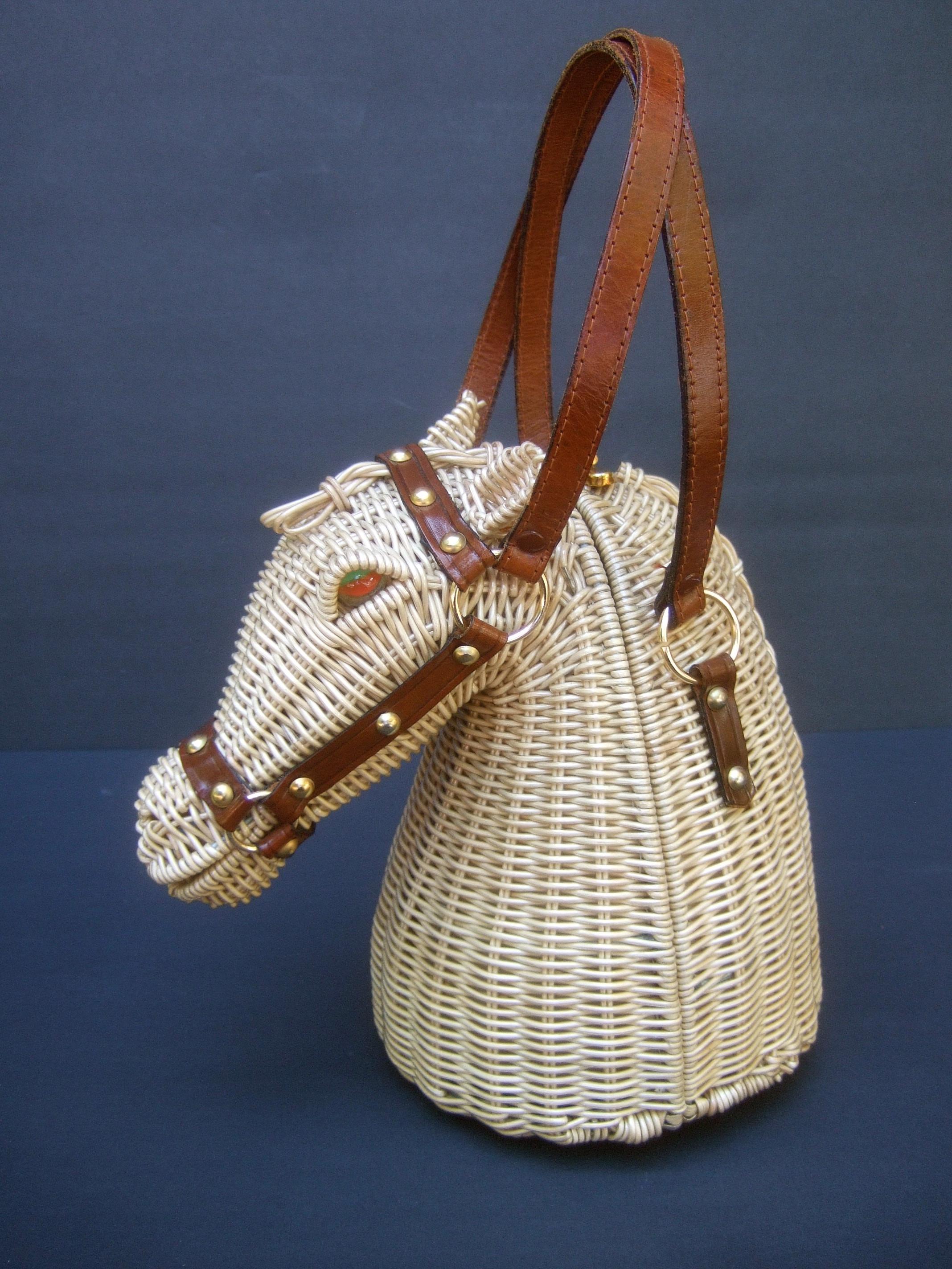 Extremely rare figural wicker artisan horse design handbag c 1970

The extraordinary handbag is designed in the shape of a majestic horse figure; embellished with fiery red & green marble glass eyes. Adorned with brown leather bridals with brass