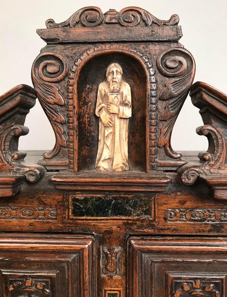 An extremely rare French carved walnut miniature meuble à deux corps. Henri II period (1519-1559).

This sixteenth-century French cabinet is inlaid with variegated marble panels, and is of distinctly architectural design characteristic of the