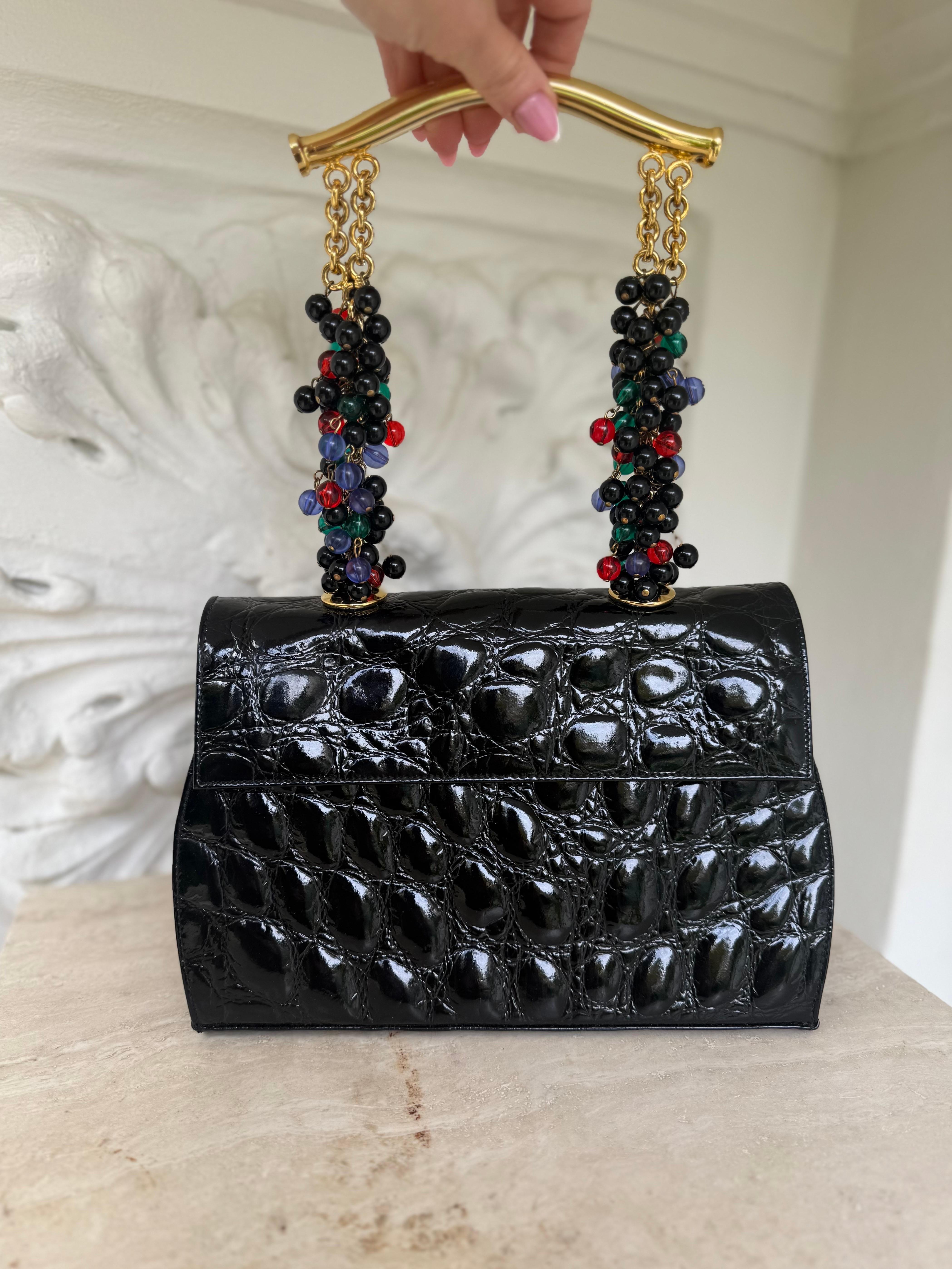 Rarísimo bolso joya documentado Gianni Versace Couture Primavera/Verano 1991 de edición limitada. 
Composición exterior: piel de becerro con relieve de cocodrilo, interior: ante. 
Asa chapada en oro, enjoyada con cuentas de cristal.
Las medidas: