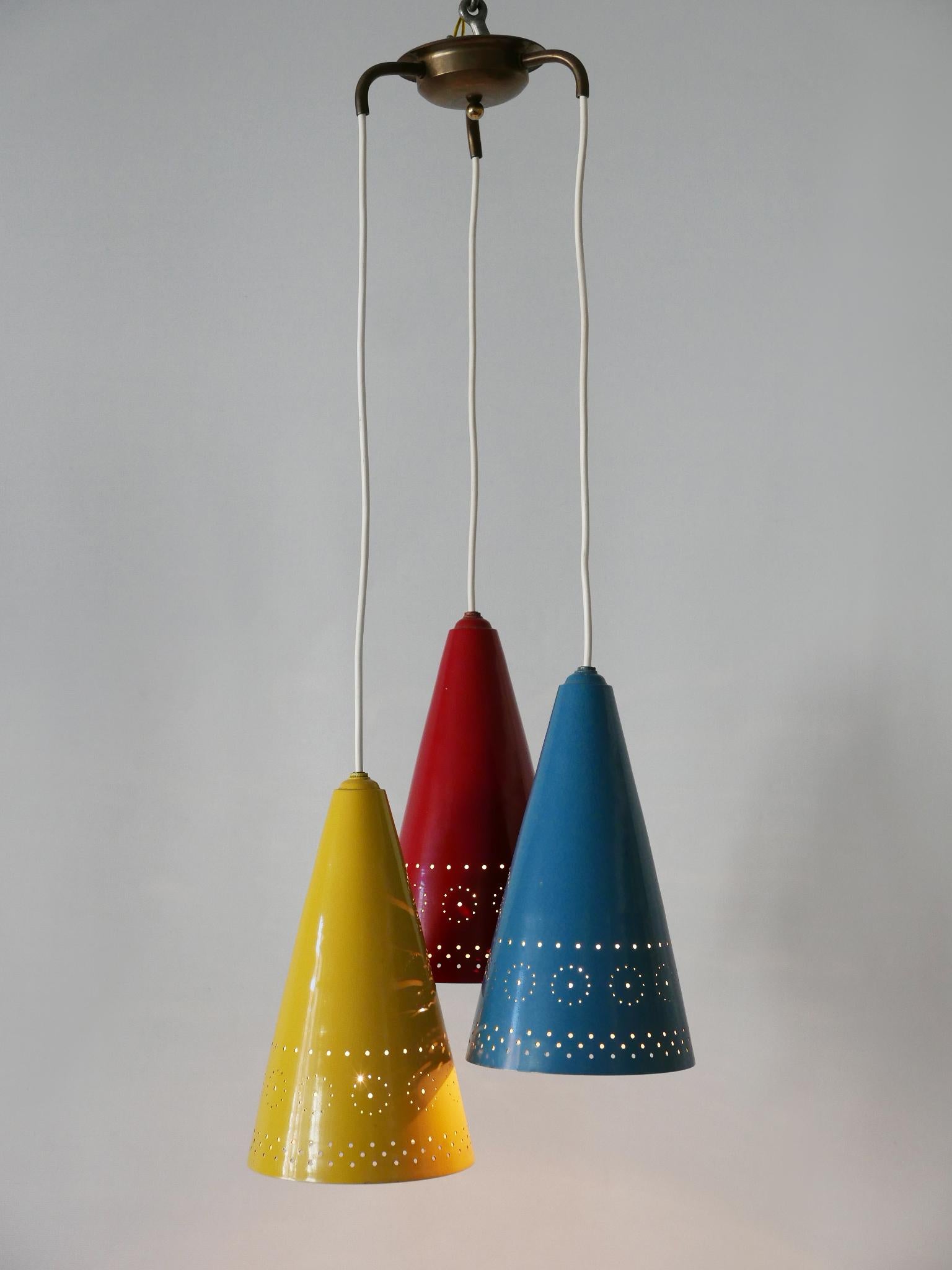 Exceptional, highly decorative Mid-Century Modern pendant lamp or hanging light with three lamp shades. Designed and manufactured in Germany, 1960s.

Executed in blue, red and yellow enameled and perforated aluminum and brass, the cascading pendant