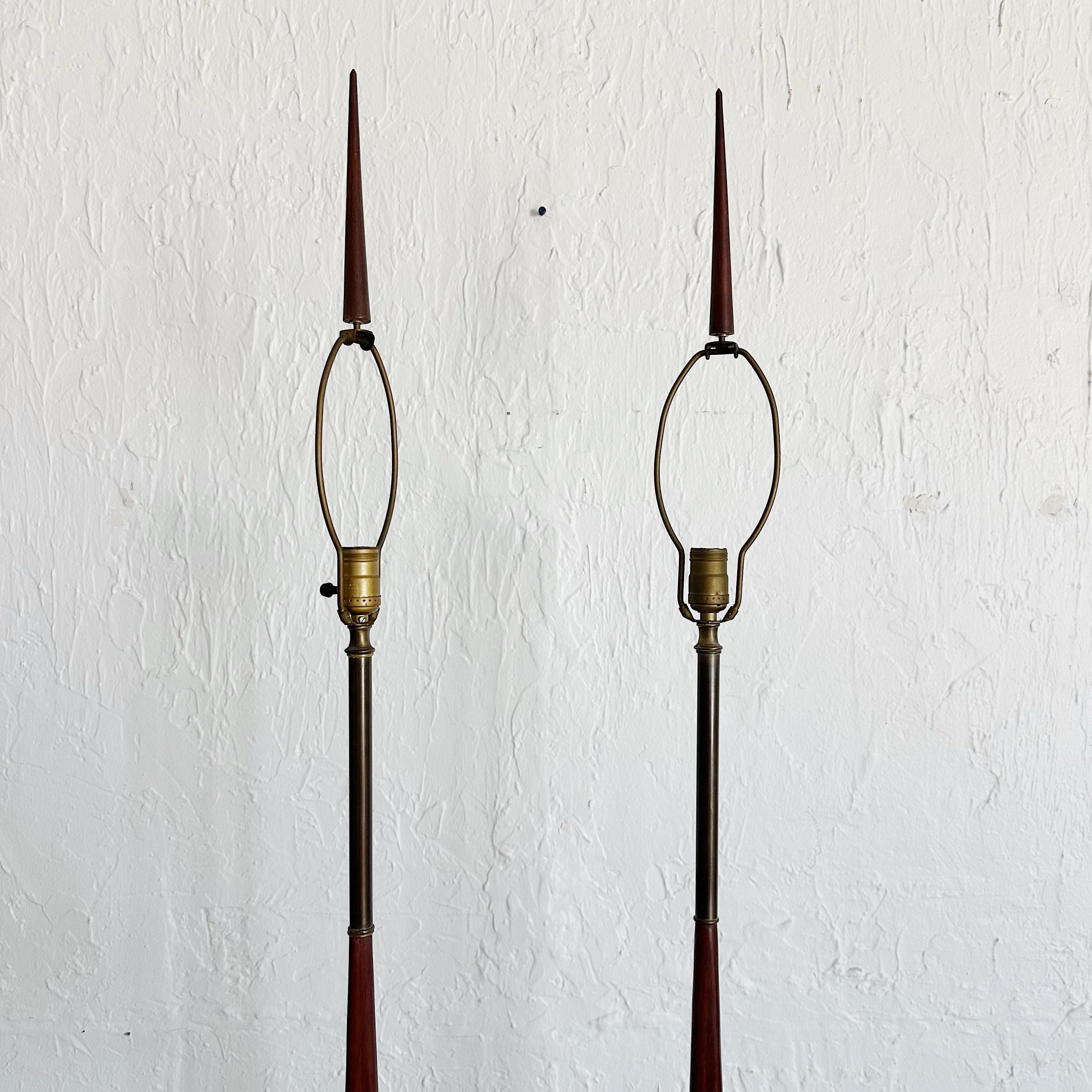 Unusually tall thin table lamps from the 1950's. Made of walnut and brass. They have the original large walnut conoid finials. Of unknown origin. Most likely American. Original wiring in working condition. In great vintage condition with patina to