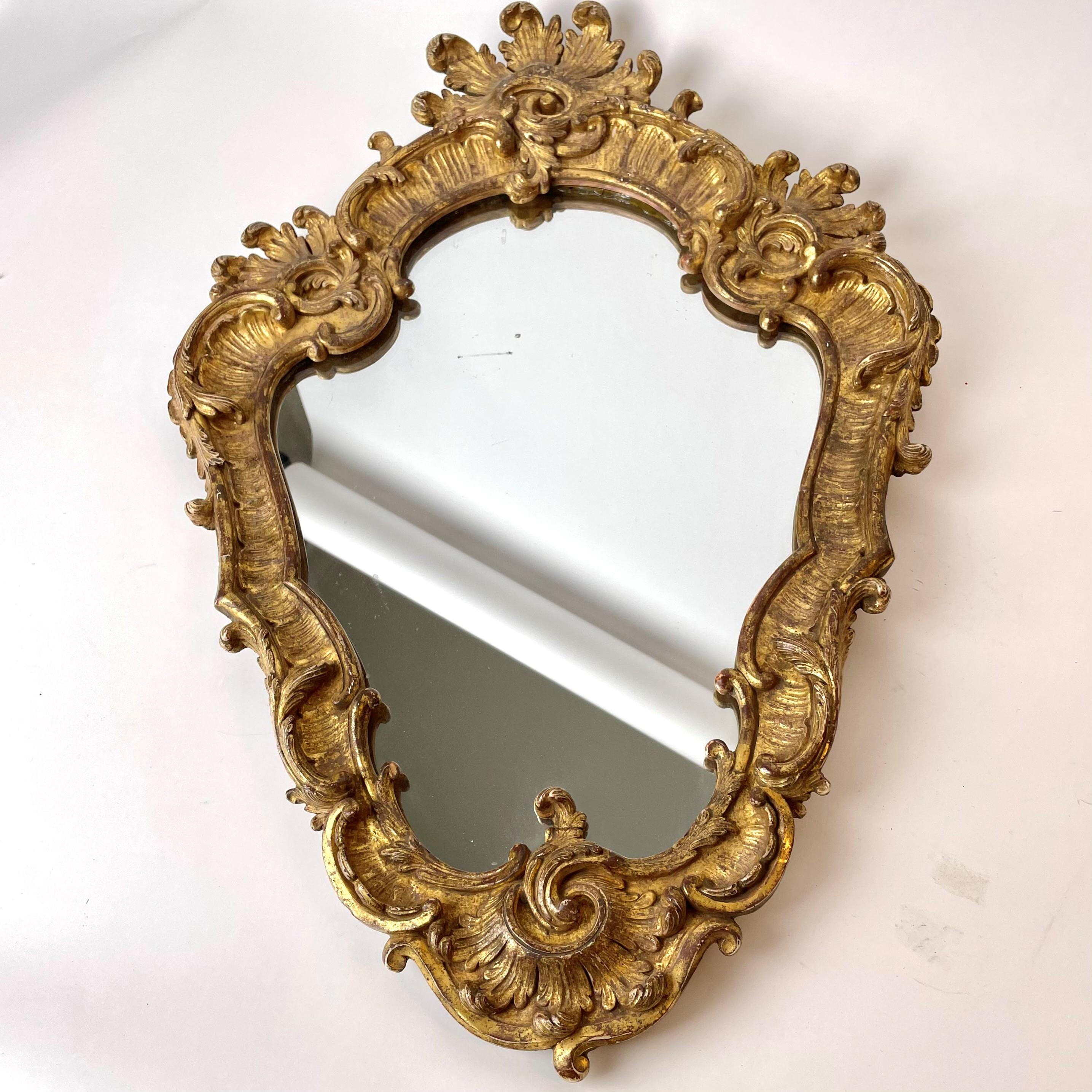 Sehr eleganter französischer Rokokospiegel mit Originalvergoldung. Wahrscheinlich um die Mitte des 18. Jahrhunderts in Paris, Frankreich, hergestellt.

Schöne Originalvergoldung mit schöner Patina. Das Spiegelglas ist wahrscheinlich ebenfalls