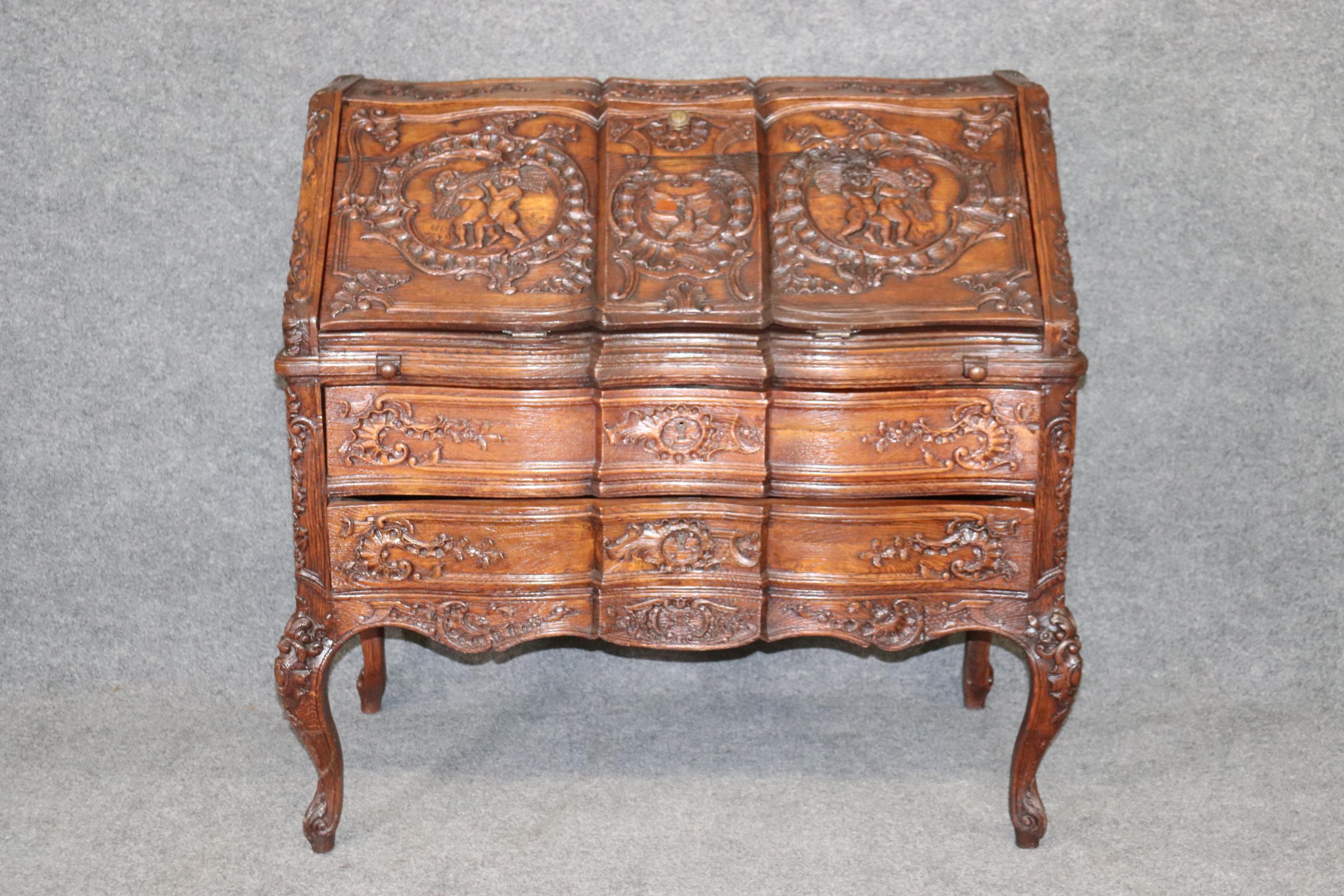 This is a fantastic and unbelievably exuberantly carved solid oak secretary desk with frolicking cherubs and incredible carving for an oak desk. Usually this kind of crisp carving is reserved for easier to carve woods such as walnut or mahogany, not